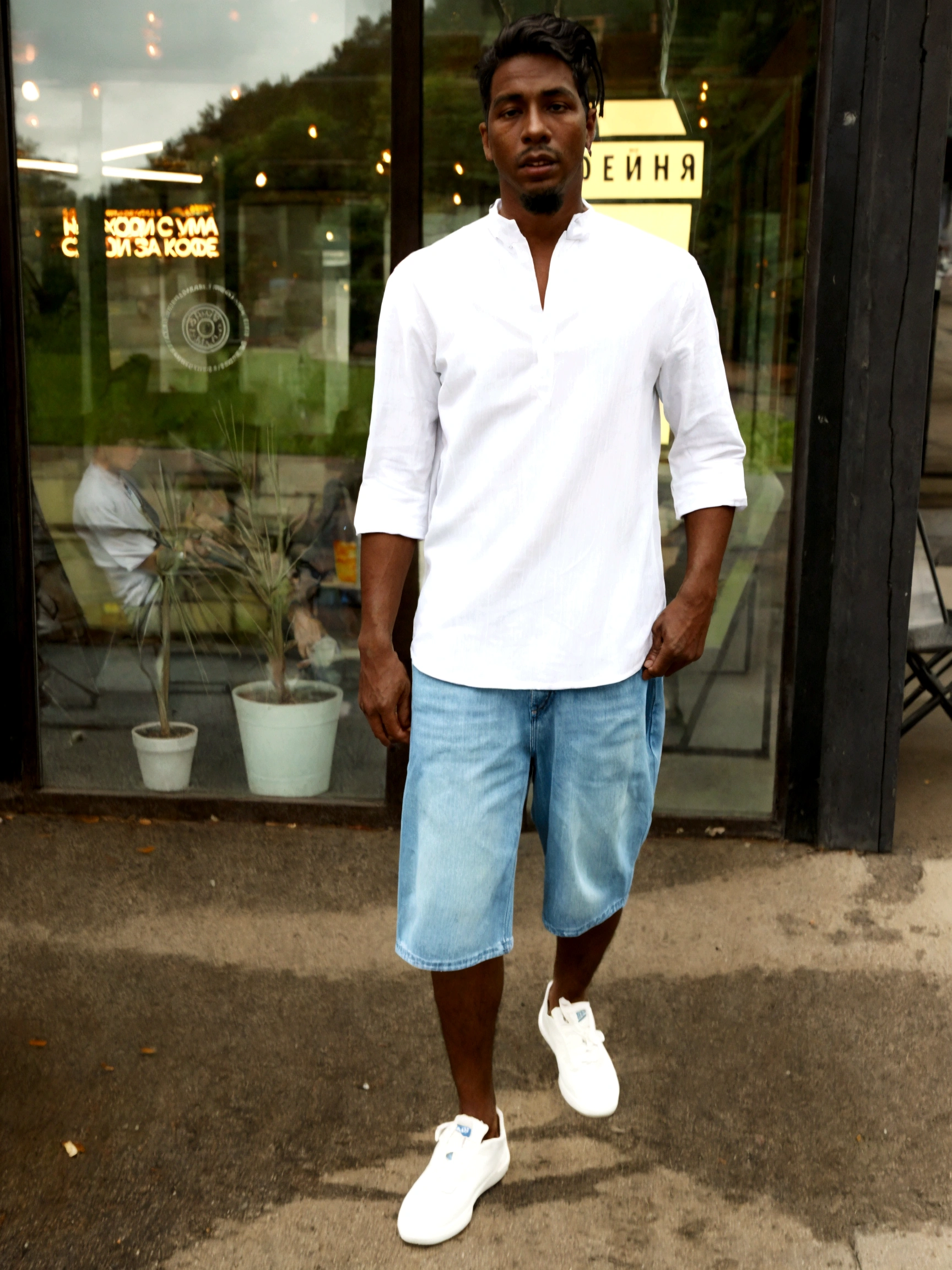 a man stands near the store with his hands in his pockets, wear a linen shirt, White shirt and blue jeans, on the street, on the street, young man with short sleeves, In the style of Davey Adesida, inspired by Theo Constante, White shirt and jeans, wear - white style, realistic style