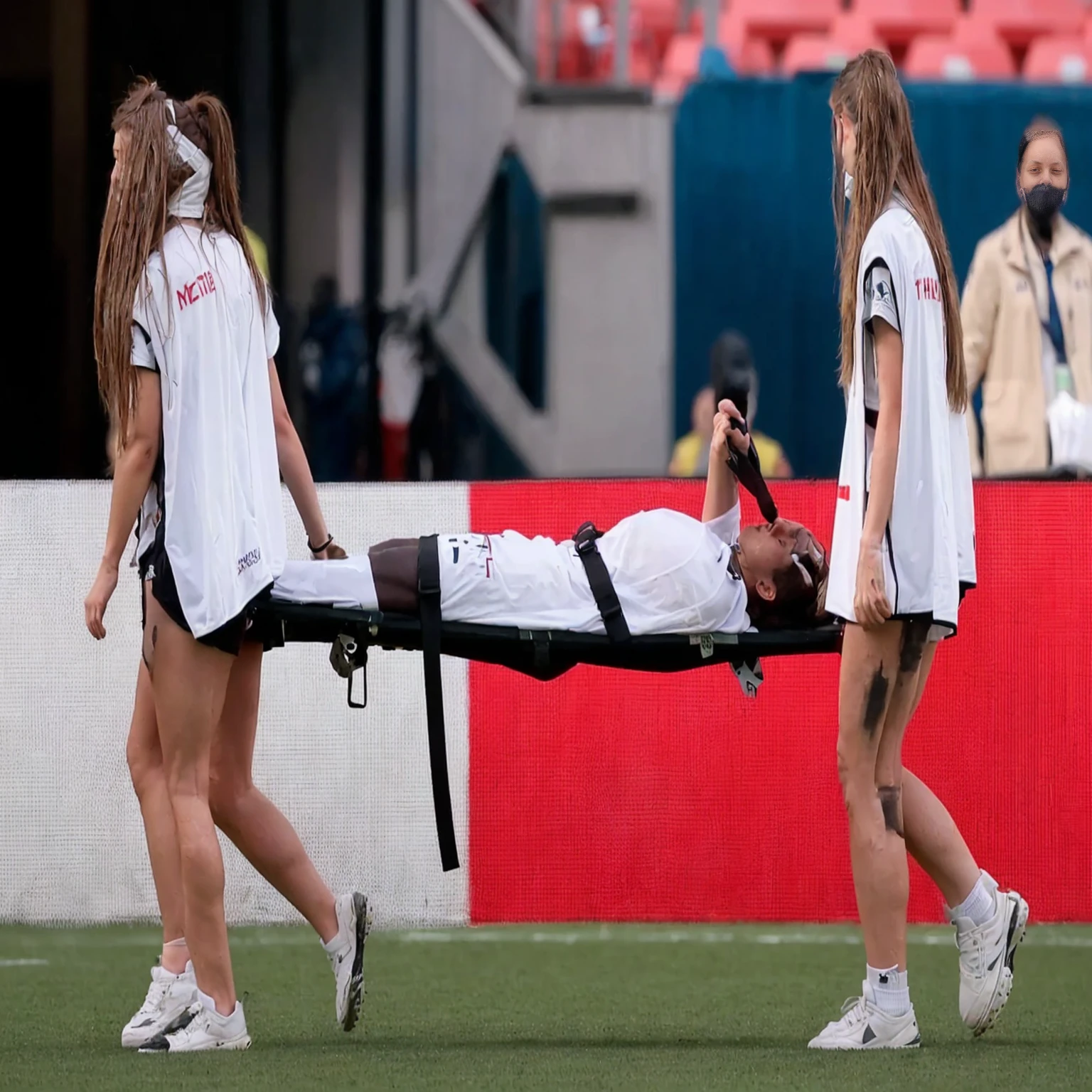 a soccer scene in a sports stadium, cool and wet weather conditions, humide ground, rainy sky, injury scene in a sports stadium, stretcher carry, there are four female medics carrying a stretcher, there are four female medics in very shiny coats who are carrying a stretcher in a sports stadium, there is a wounded male soccer player in a matte short cotton sports outfit lying on the stretcher, an injured male soccer player in matte cotton sportswear is lying in pain on a stretcher, a soccer player in matte cotton sports clothes is rearing up in intense pain while lying on a stretcher, dramatic scene, theatralic posing scene, dramatic pity scene, injury soccer, first aid, help, pity, there are four female medics in wetlook high-shine coats who are looking very sad and very terrified and very shocked, the injured soccer player is screaming out in pain while he is carried from the pitch on a stretcher