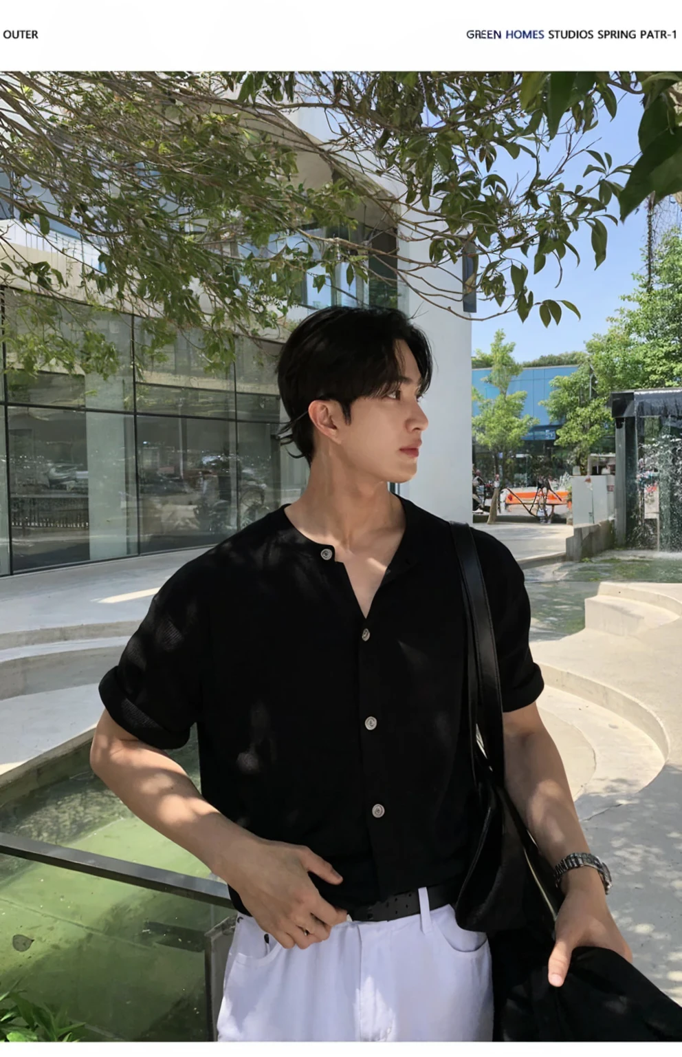 Portrait of a stylish young man with a cafe in the background。He was wearing a grey short-sleeved T-shirt and black pants.、It has a simple and modern style。His hair is neatly black.。His expression is serious、Facing to the side。A fashionable streetscape in the background。I feel class in the silver necklace.。He has a black jacket in his hands。The contrast of light and shadow makes his outline stand out.。