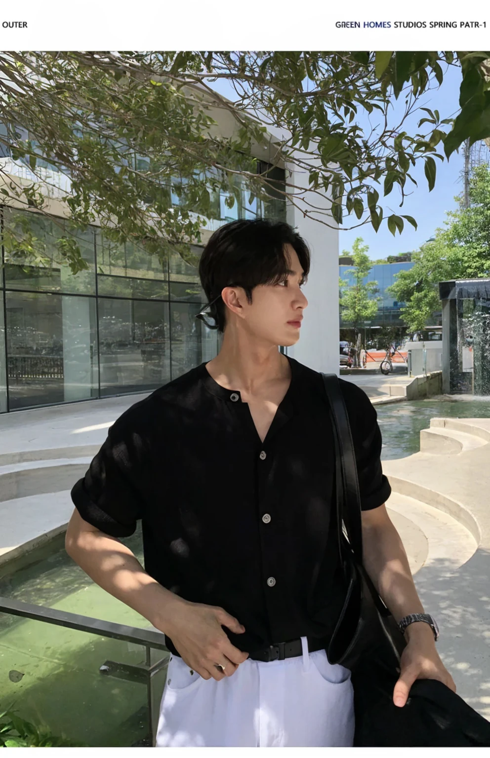 Portrait of a stylish young man with a cafe in the background。He was wearing a grey short-sleeved T-shirt and black pants.、It has a simple and modern style。His hair is neatly black.。His expression is serious、Facing to the side。A fashionable streetscape in the background。I feel class in the silver necklace.。He has a black jacket in his hands。The contrast of light and shadow makes his outline stand out.。
