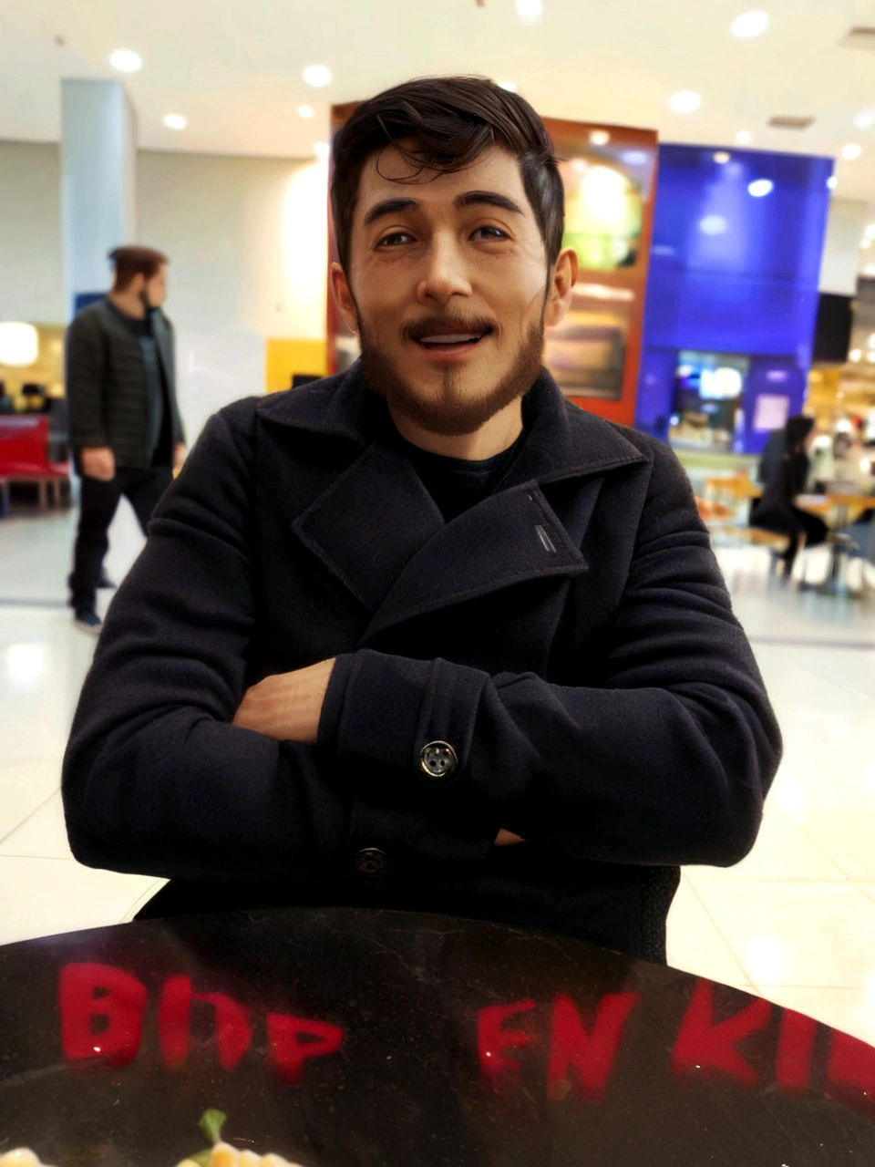 thin man with a beard sitting with his arms crossed smiling in a shopping mall