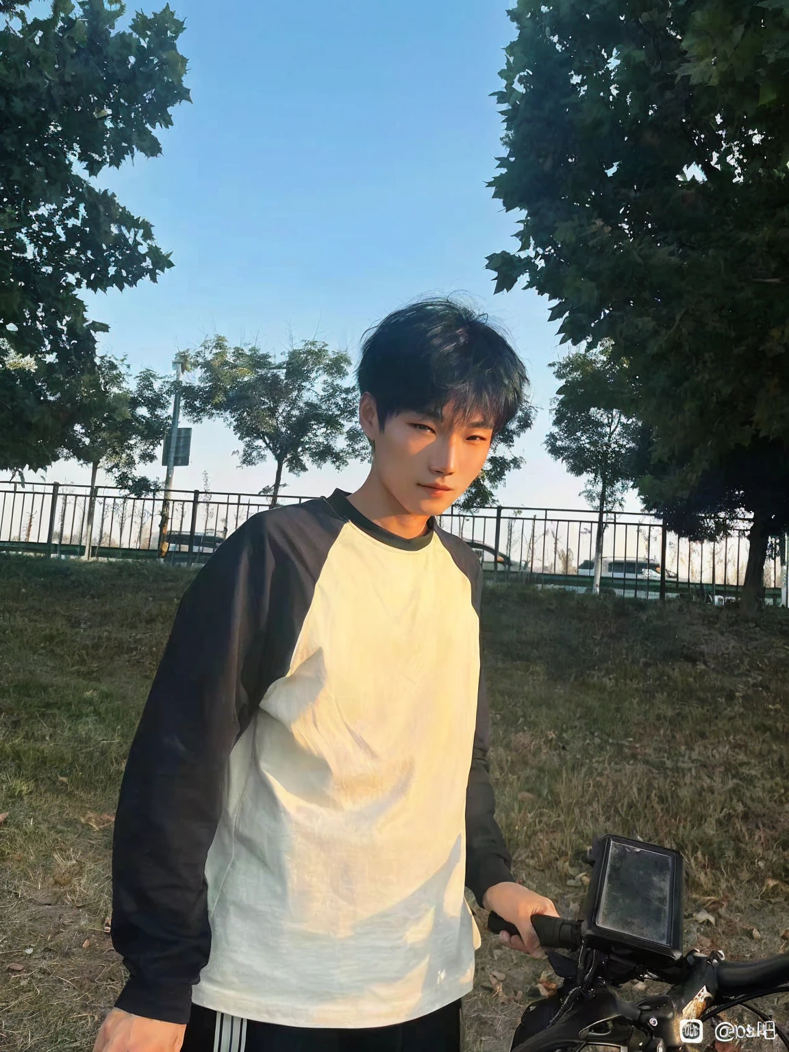 Young man in Arav standing next to his bicycle in the park, xintong chen, Bat Ulzan, Kim Do-young, As the sunset, Cheng Man Kit, yanjun chengt, In sunny weather, Wenjun Lin, cai xukun, short hair, Very very low quality image, Profile picture 1024px, The afternoon light is beautiful