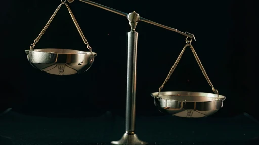 The scales of justice completely unbalanced, black background, cinematic format