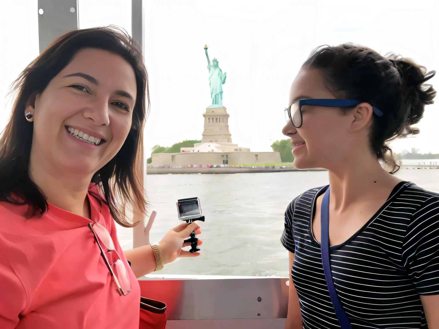 woman holding a cell phone and smiling at the camera, on liberty island, statue of liberty at left, statue of liberty, photo of the statue of liberty, the statue of liberty, in the middle of new york, liberty statue sitdown pose, tourists in background, usa-sep 20, scenic full shot, interior of staten island ferry, very accurate photo