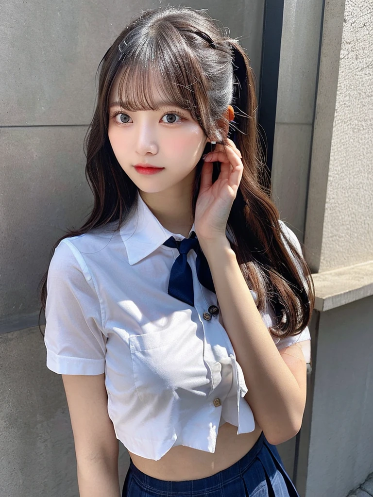 The image features a young woman standing against a plain, light background. She has long, straight dark hair styled into two buns on the top of her head, with some strands left loose framing her face. Her expression is neutral, with a slight hint of curiosity or attentiveness. She is wearing a short-sleeved, white, button-up shirt that is tied above her navel, revealing her midriff. The shirt has a single pocket on the left side, adorned with a navy blue tie that complements her attire. Below, she wears a light blue pleated skirt that falls mid-thigh, completing a school-uniform-inspired look. The lighting is soft and natural, coming from the left side, creating gentle shadows and highlighting the details of her outfit and facial features. The overall atmosphere is calm and minimalistic, focusing on the subject with no distracting elements in the background.