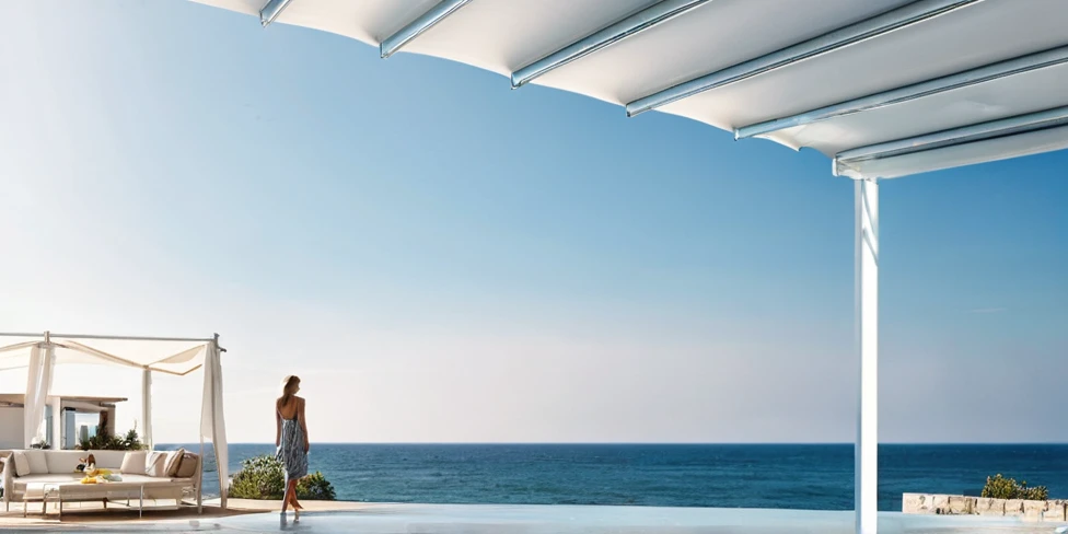 there is a woman standing on a deck Overlooking the sea, Awnings, Canopies, looking at the ocean, Next to it is the reflected ocean, Overlooking the sea, In the seaside environment, Award-winning shadows, The award-winning", Close to the sea, Award-winning masterpiece, Sea view, Looking to the horizon, looking at the ocean