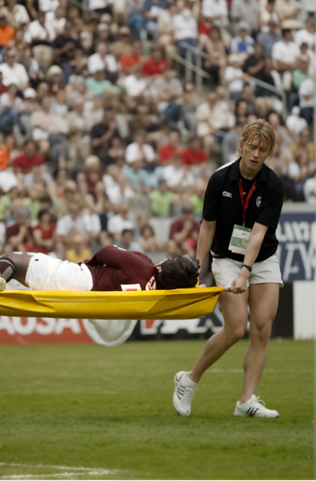 a blond woman is carrying a astretcher on a soccer field, there is a male soccer player in short sportswear lying injured on a stretcher, there is an injured sportsman who is covering his face on a stretcher, an injured sportsman is covering his face with his hands, an injured sportsman is writhing ecstatic in pain on a stretcher, dramatic pity pose, there is a very female woman in a high-shine coat, a high-shine black wetlook coat, a long shiny coat, a wetlook glossy coat, a wet black laquered coat, a very female looking wife is wearing a wetlook coat, injured, medic, soccer action pose, affection pose, lecherous action pose, dramatic action pose, theatralic pose, there is an attractive woman that is carrying a suffering man on a stretcher, there is a beautiful woman in a shiny coat who is carrying a blond man on a wet orange stretcher, a longhaired beautiful woman in a high-shine coat, a longhaired woman in a shiny downcoat, a woman is carrying a stretcher with a shorthaired man who is wearing shorts and a t-shirt, a weak man in spots shorts is consciousless and needs to be carried on a wetlook pvc stretcher, a shorthaired man with closed eyes is carried on a stretcher by a longhaired woman, a woman looks very scared and terrified, a consciousless man with closed eyes is suffering very much and has a very painful face, photo, photo shoot, photographed , accident, help, aid, first aid, pity