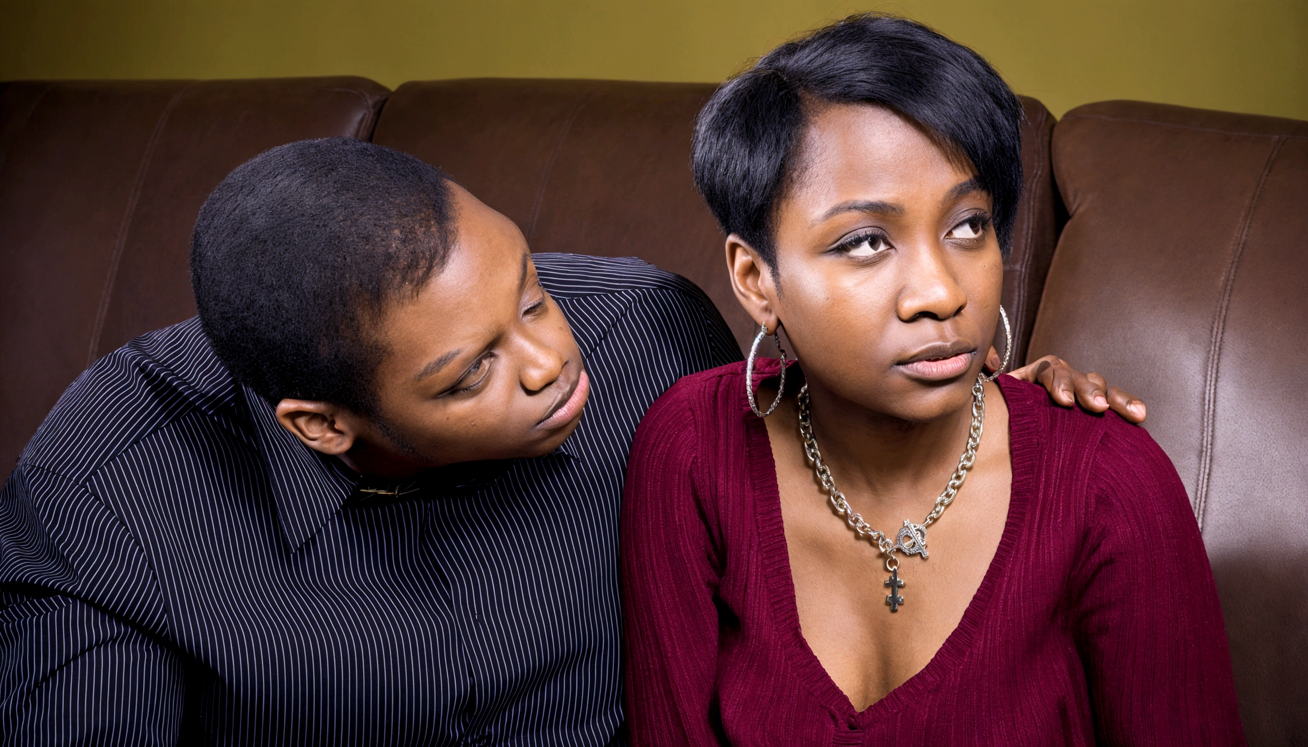 (( young black male pastor wearing a large cross pendant, clergy collar, and robes)), in his ((living room:1.4)) accompanied by a ((50 year old busty and slutty black church mother:1.3))