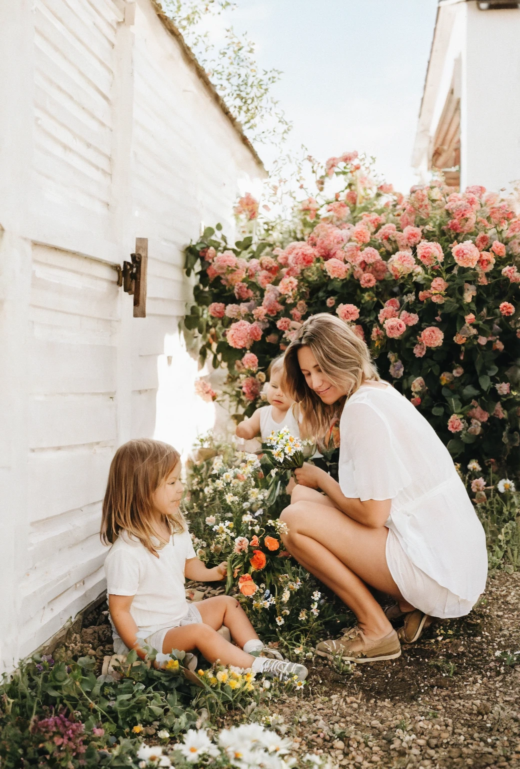 there is a woman and a sitting on the ground, picking up a flower, picking flowers, sitting with flowers, with flowers, holding flowers, flowers around, in the garden, with a kid, beautiful photo, beautiful image, motherly, photo of a beautiful, summer afternoon, summer morning light, having a good time, girl in flowers, beautiful view
