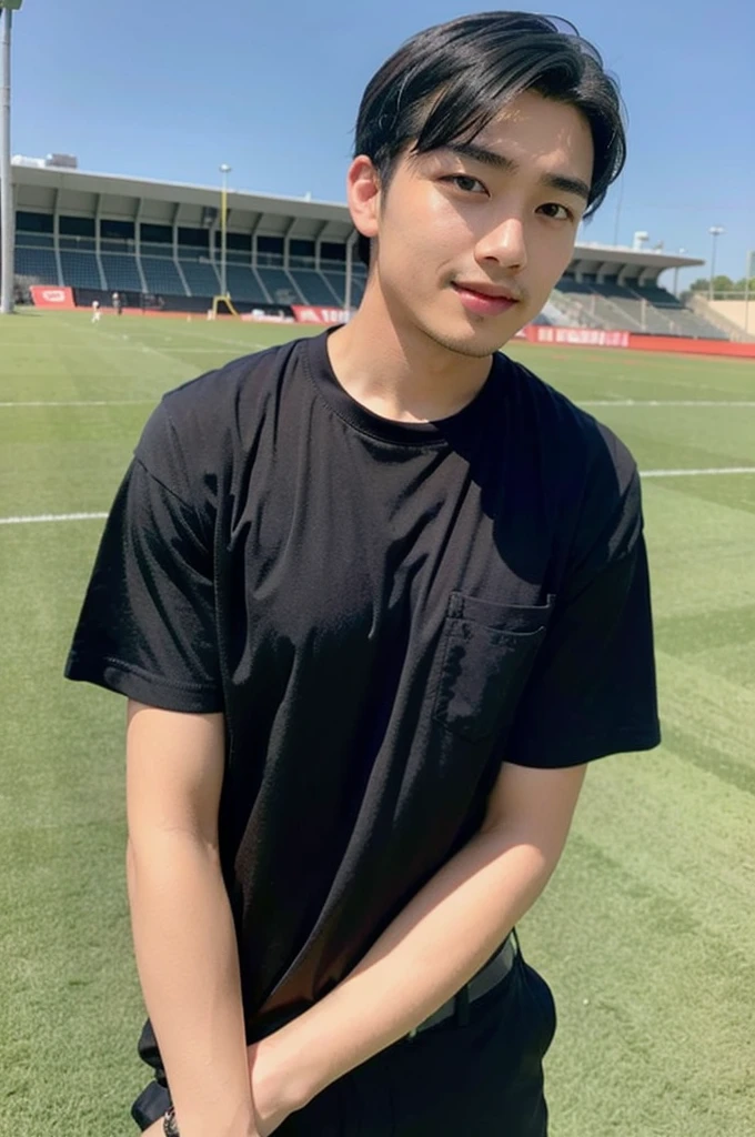young asian man looking at camera In a black button-down shirt , Fieldside, beach, sunlight, looking at the football field
