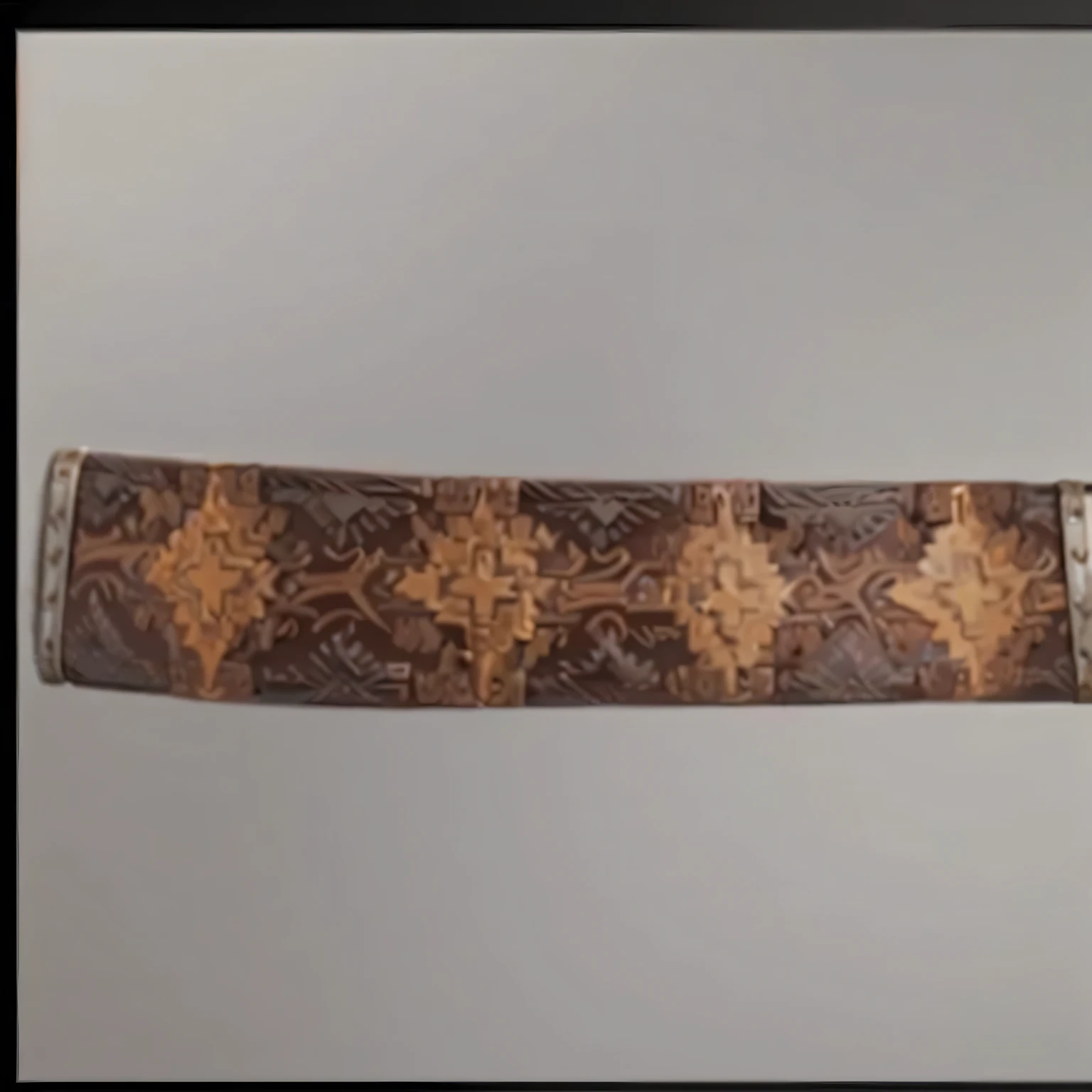 there is a photo of a bracelet with a cross pattern, with blunt brown edge, silk belt,, mid 19th century, Hand painted textures on the model, bandolier, complex pattern, zoomed out to show full image, leather bark armor, wide establishing shot, close establishing shot, leather art