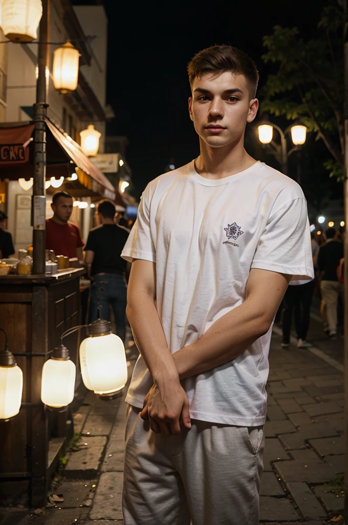 a young man of Slavic appearance on the street in the evening under the light of lanterns in the city in a white T-shirt