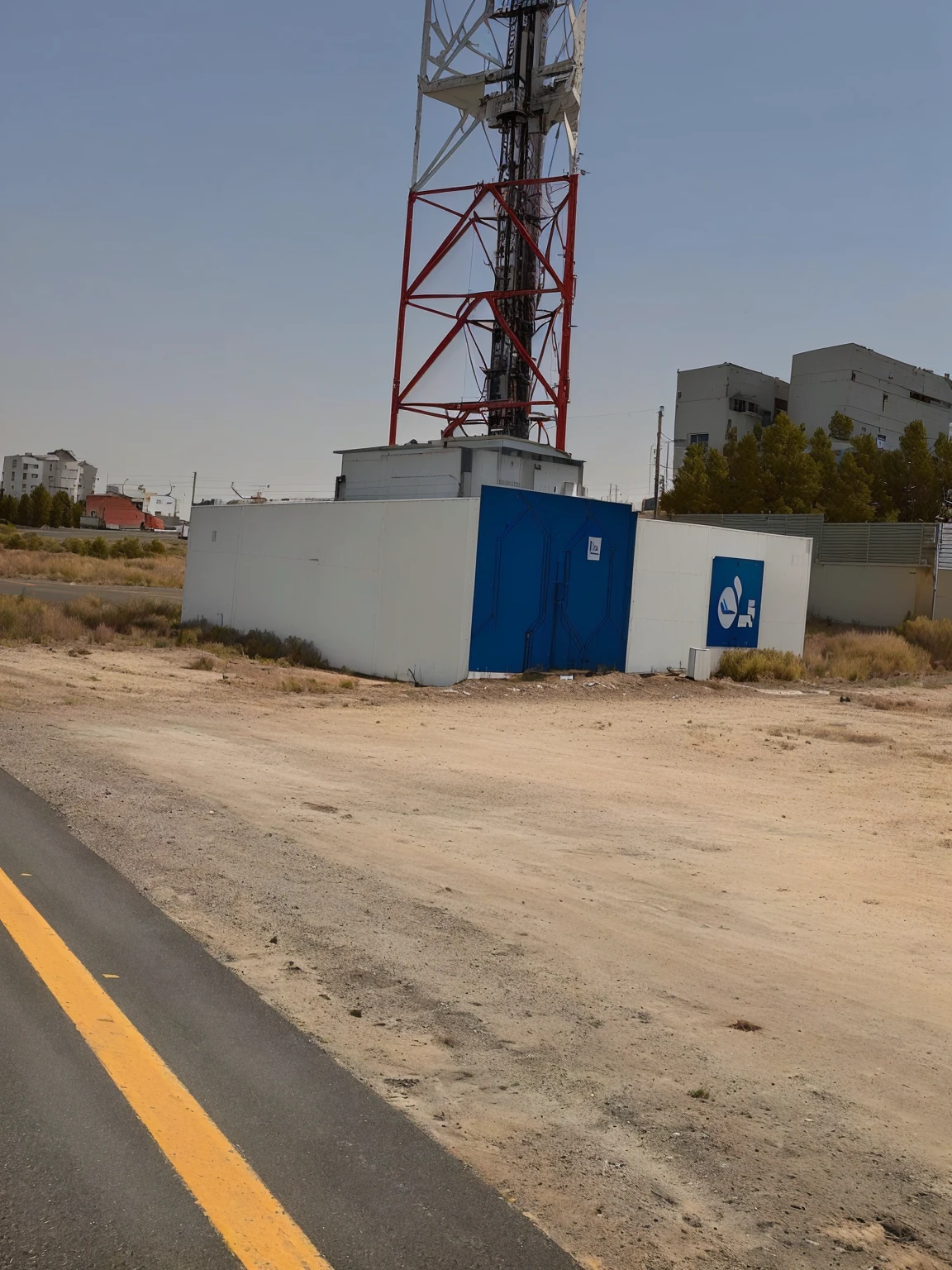 there is a cell tower on the side of the road, ( land ), photo from 2022, by Daarken, by Dr. Atl, very very low quality picture, unusual composition, building in the distance, photograph taken in 2 0 2 0, taken on iphone 1 3 pro, detailed wide shot, mid-view, interesting composition, large view