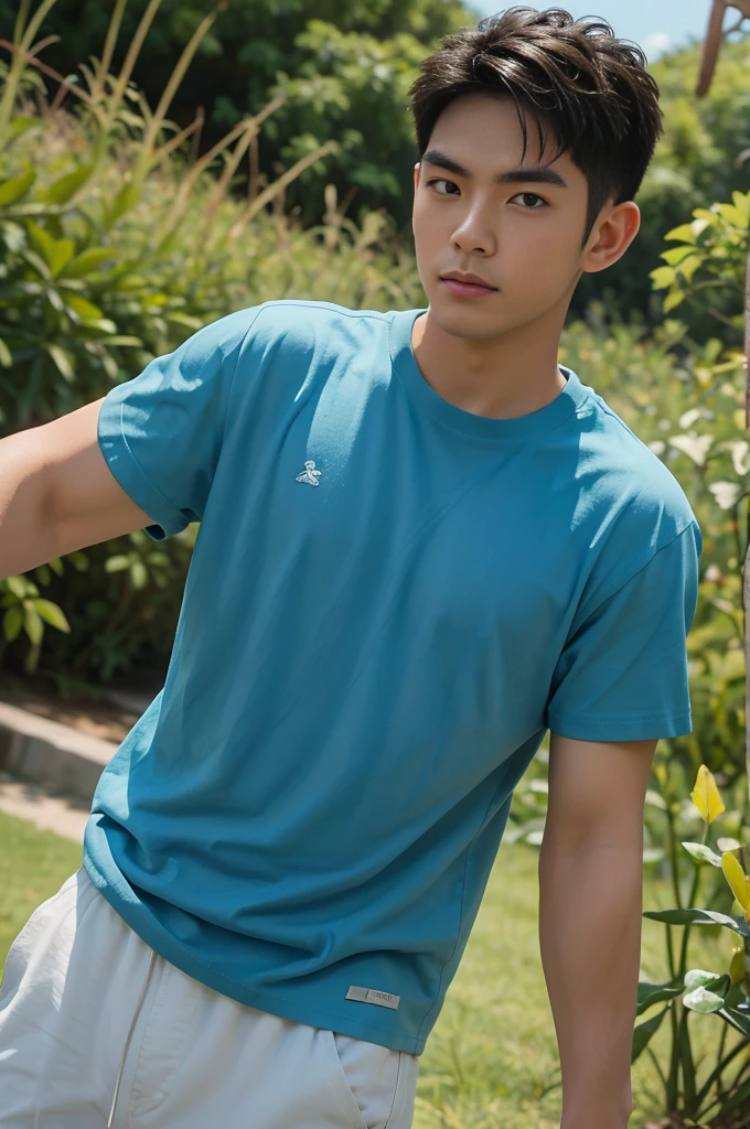 A handsome, muscular young Asian man looks at the camera. In a simple blue t-shirt , Fieldside, grass, beach, sunlight