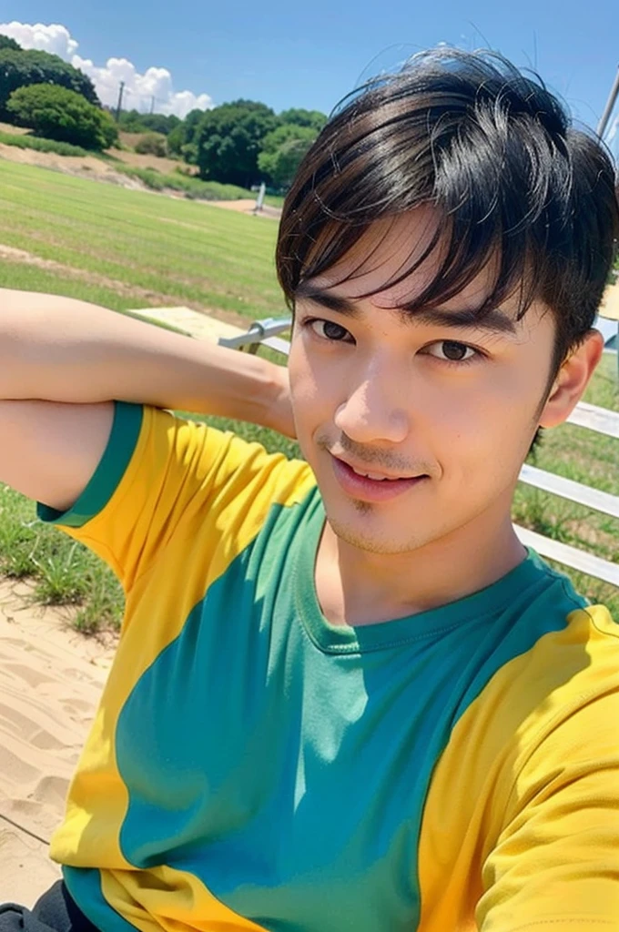 A handsome, muscular young Asian man looks at the camera. In a plain yellow t-shirt , Fieldside, grass, beach, sunlight