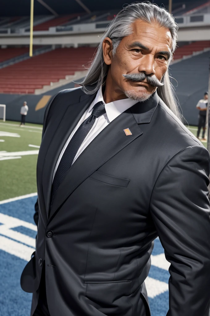 man from samoa, 60 years old, very muscular body, long gray hair, football coach, handlebar moustache, at a football field, wearing black business suit