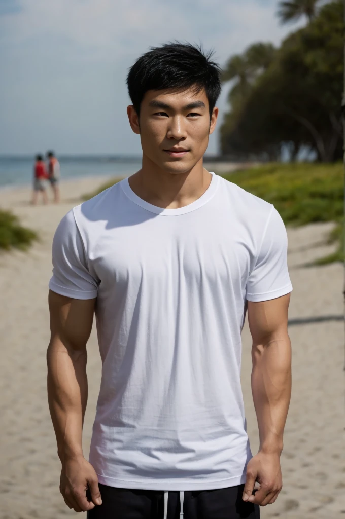 A handsome, muscular young Asian man looks at the camera. In a simple t-shirt white and red , Fieldside, grass, beach, sunlight