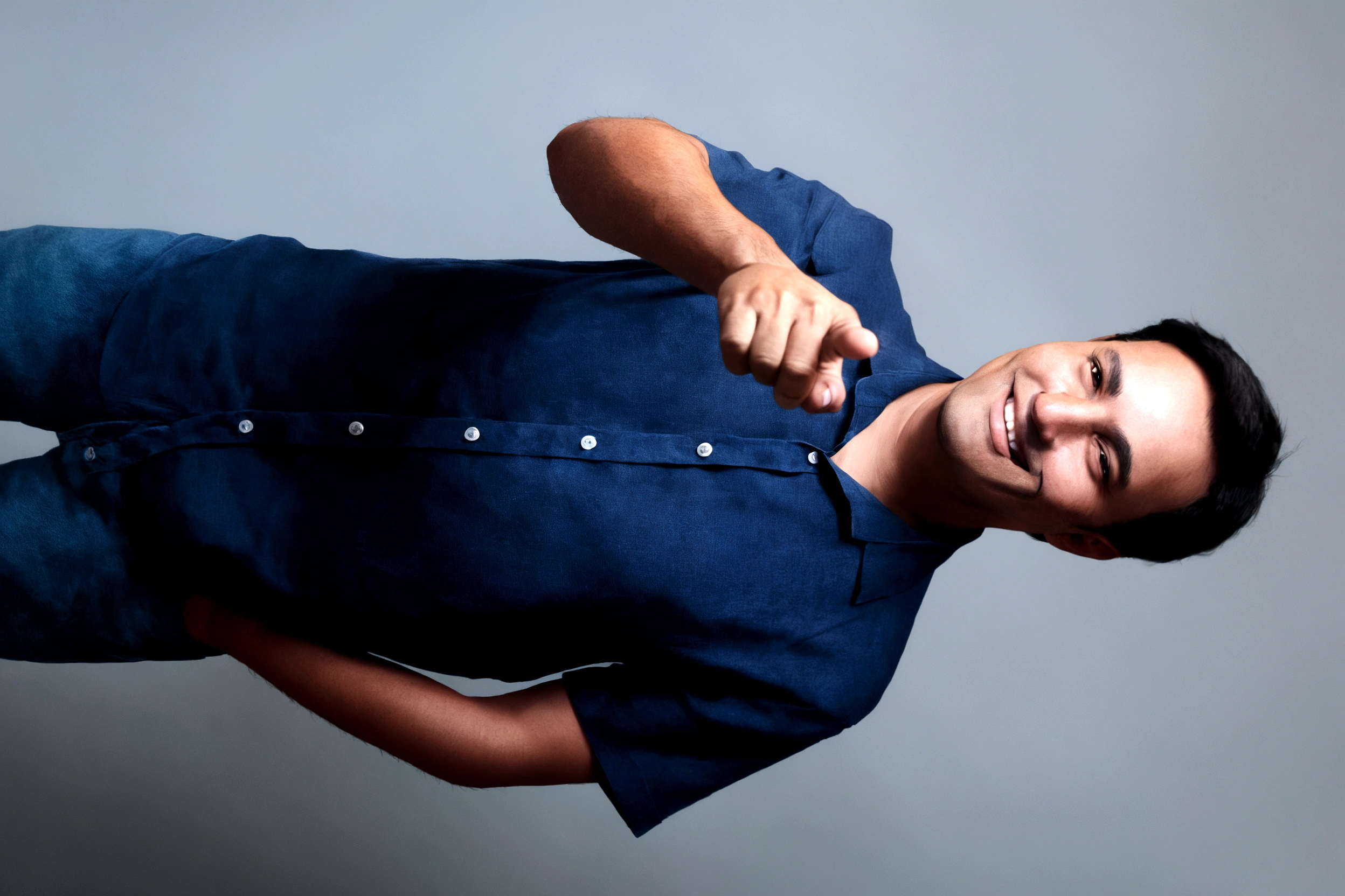 friendly man pointing finger in blue blouse smiling