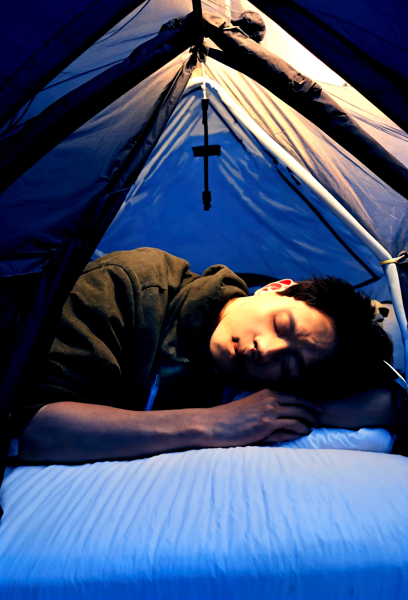 Draw me a Korean man sleeping in a tent on a dark night