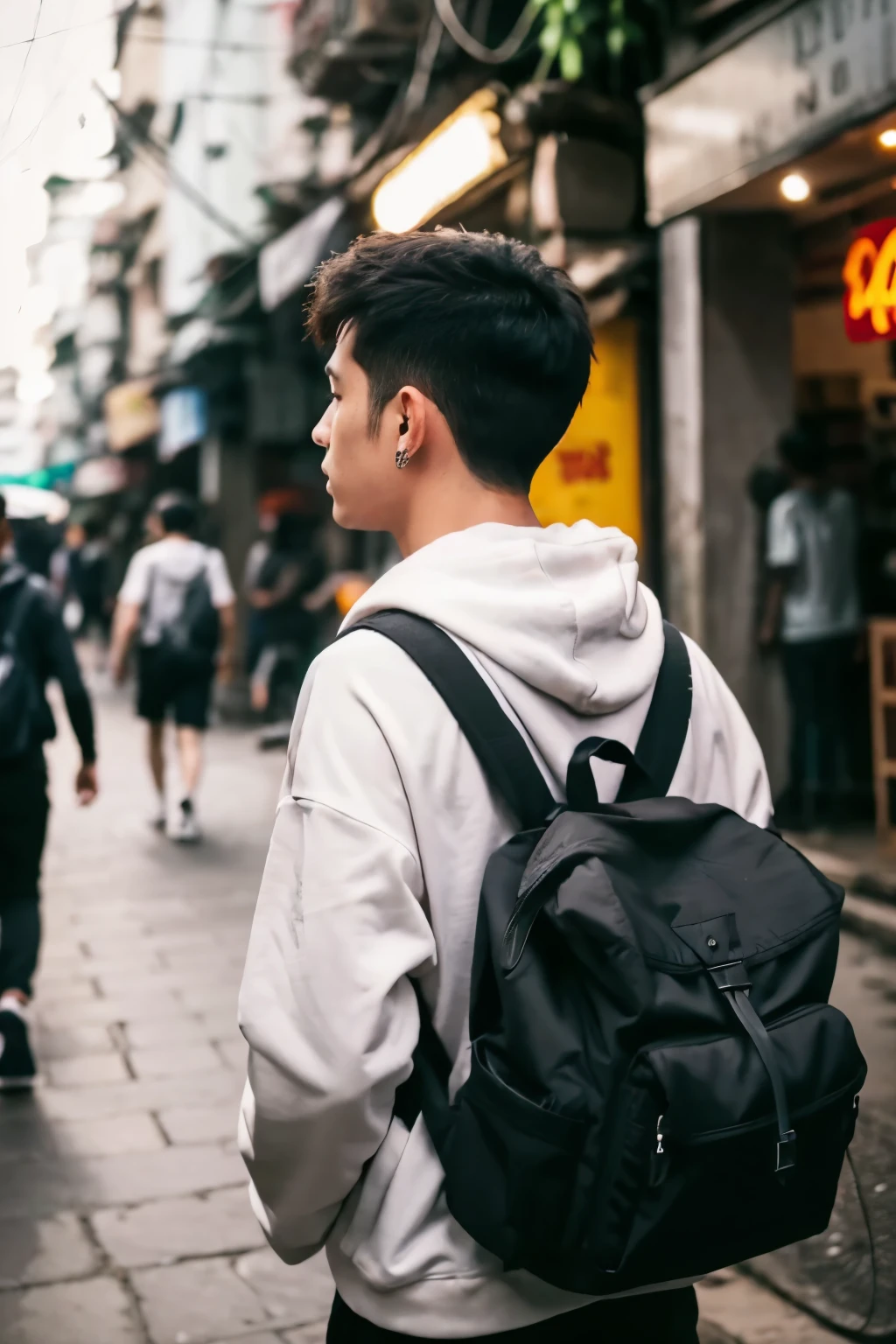 A man, with a disheveled tapered hairstyle, wears a hoodie and jogger, streetwear style, taken from behind, carrying a black backpack on hire in the street of Vietnam with few people.