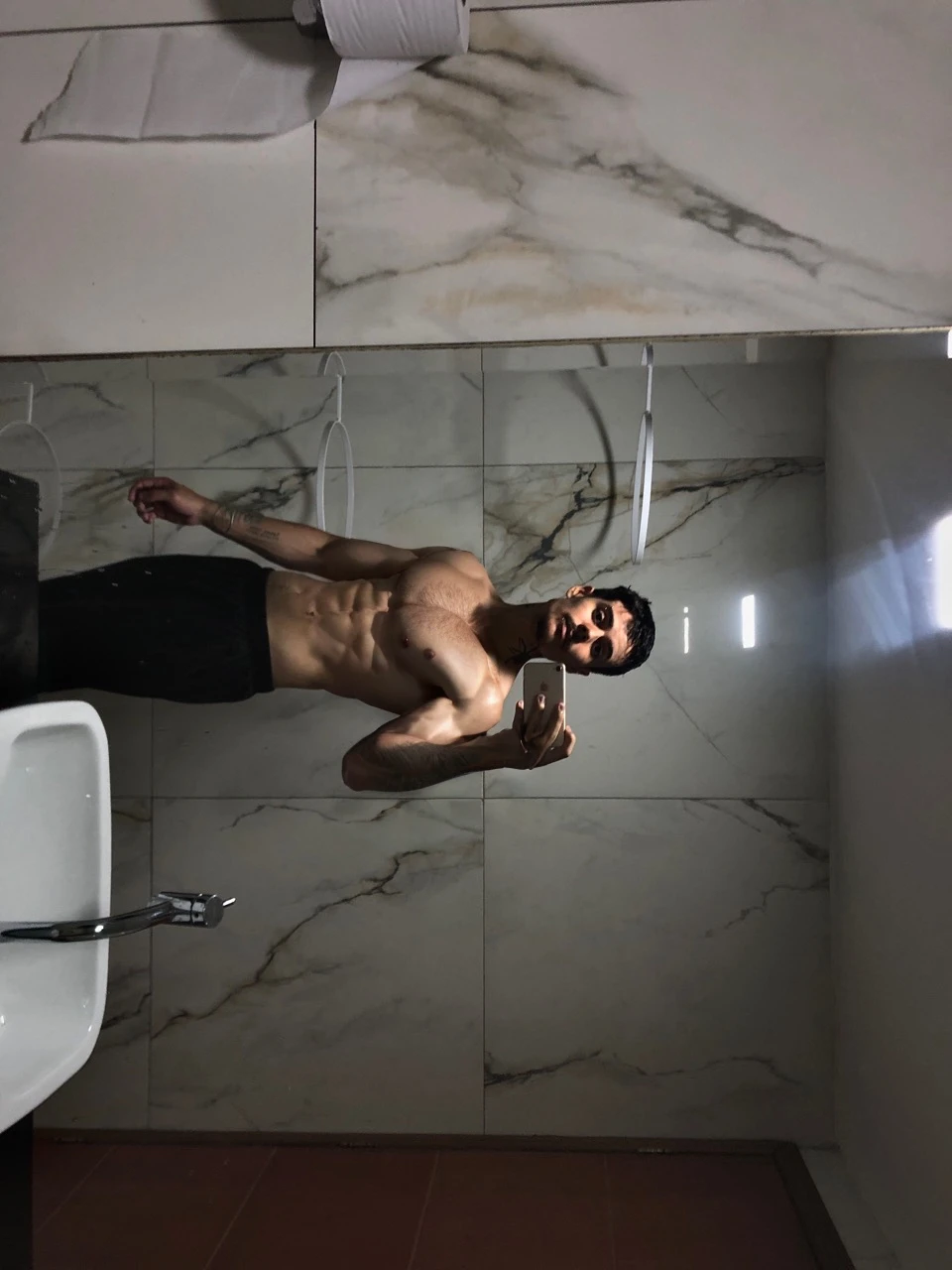 a 17 year old boy,short black hair,intense blue eyes,intense gaze,defined facial features,no facial hair,tall muscular build,broad shoulders,v-shaped body,wolf tattoo on right arm,full body focus,completely hairless,(best quality,4k,8k,highres,masterpiece:1.2),ultra-detailed,(realistic,photorealistic,photo-realistic:1.37),portrait,cinematic lighting,dramatic shadows,dynamic pose,highly detailed