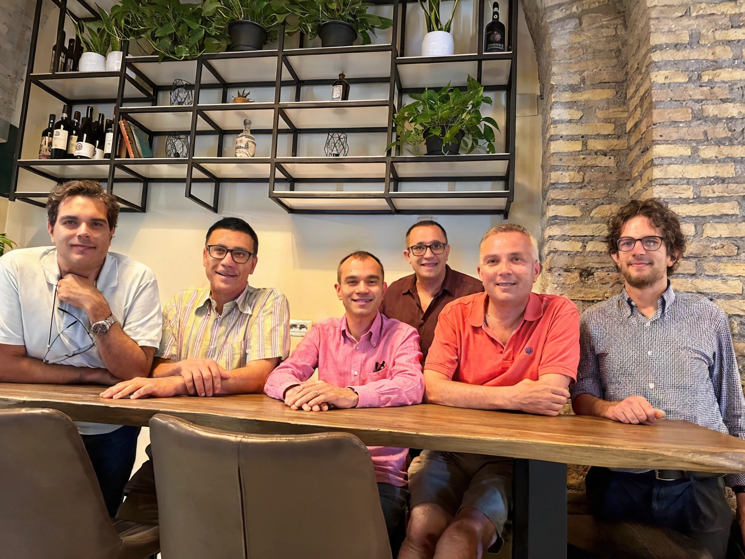 several men of around 30 yo sitting at a table with a wooden table top, high picture quality, group sit at table, taken in 2022, high quality picture,