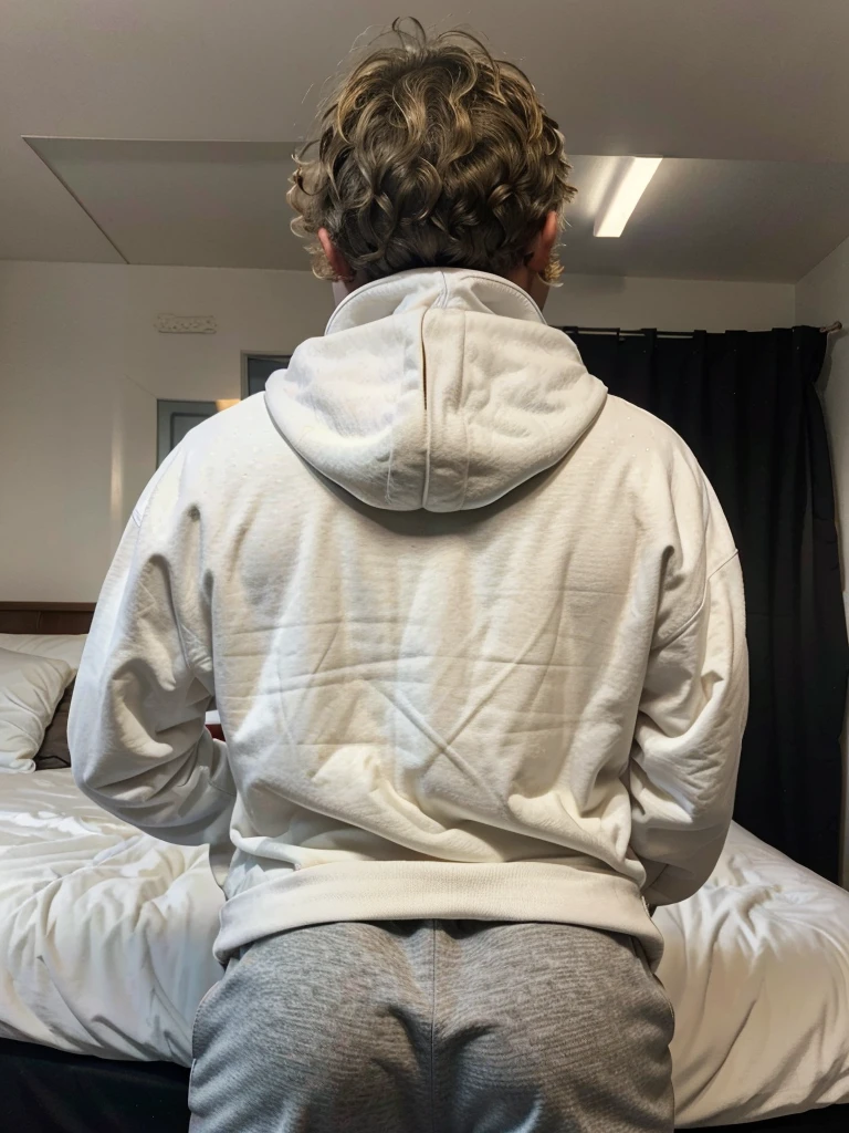 19 year old boy with a Curly medium dirty blonde hair, wearing a white hoodie with black athletic pants , inside the bedroom , freckles, back view