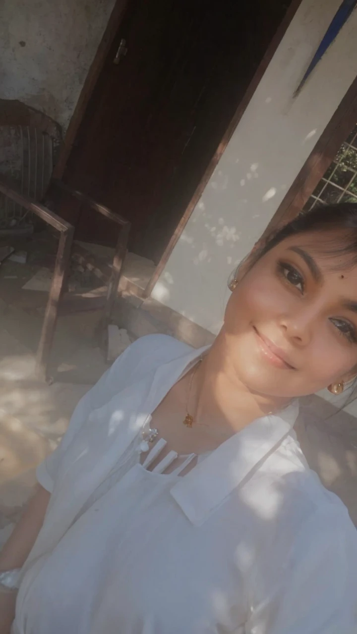 A charming indian woman, with an Off-the-shoulder shirt, Pelvic Curtain, necklace, Portraiture, bracelet, Cowboy Shot, Seductive pose, smile. Her soft dimples and realistic expression lines add authenticity. Her skin is illuminated by the sun's rays, highlighting her beauty. She is dressed in long, sophisticated clothes. In the background, there is a chaotic structure with multiple entrances, almost in ruins, surrounded by dense and branched vegetation. To capture this extraordinary scene, a high-resolution camera such as the Phase One XF IQ4 150MP is required. The lighting is diffused and natural, minimizing harsh shadows. The camera settings include a medium aperture, adjusted shutter speed, and a high-quality wide-angle lens with a focal length of approximately 35mm to capture the entire scene in an immersive way. Sharp, precise details are captured, from wavy hair to complex clothing patterns, ensuring a natural and stunning image.