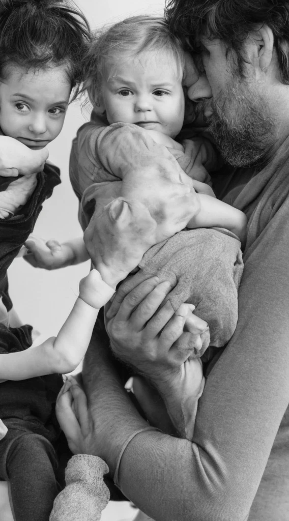 Un homme à genoux qui tient sa fille et son fils dans les bras