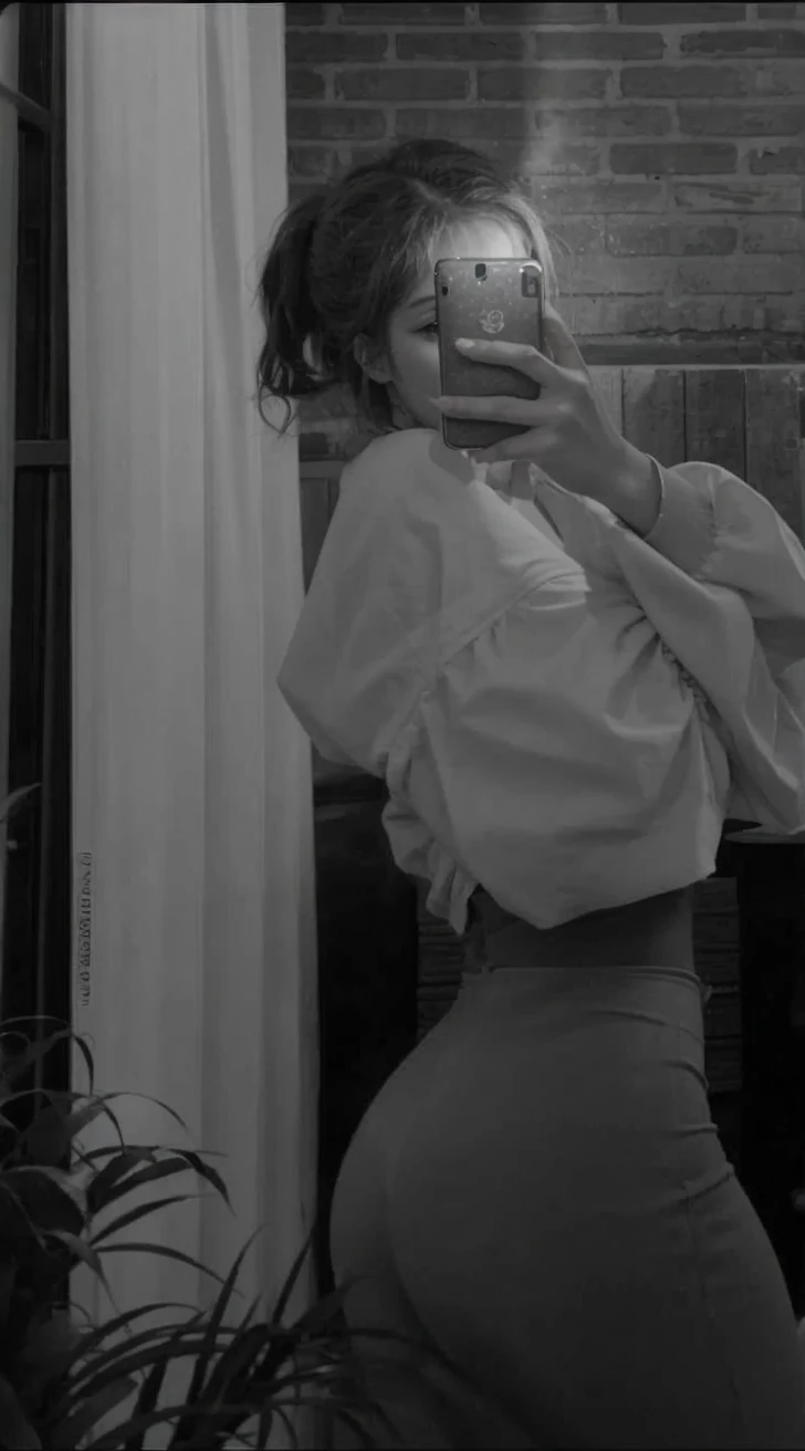 Girl taking selfie with her body sideways, with her cell phone on her face 