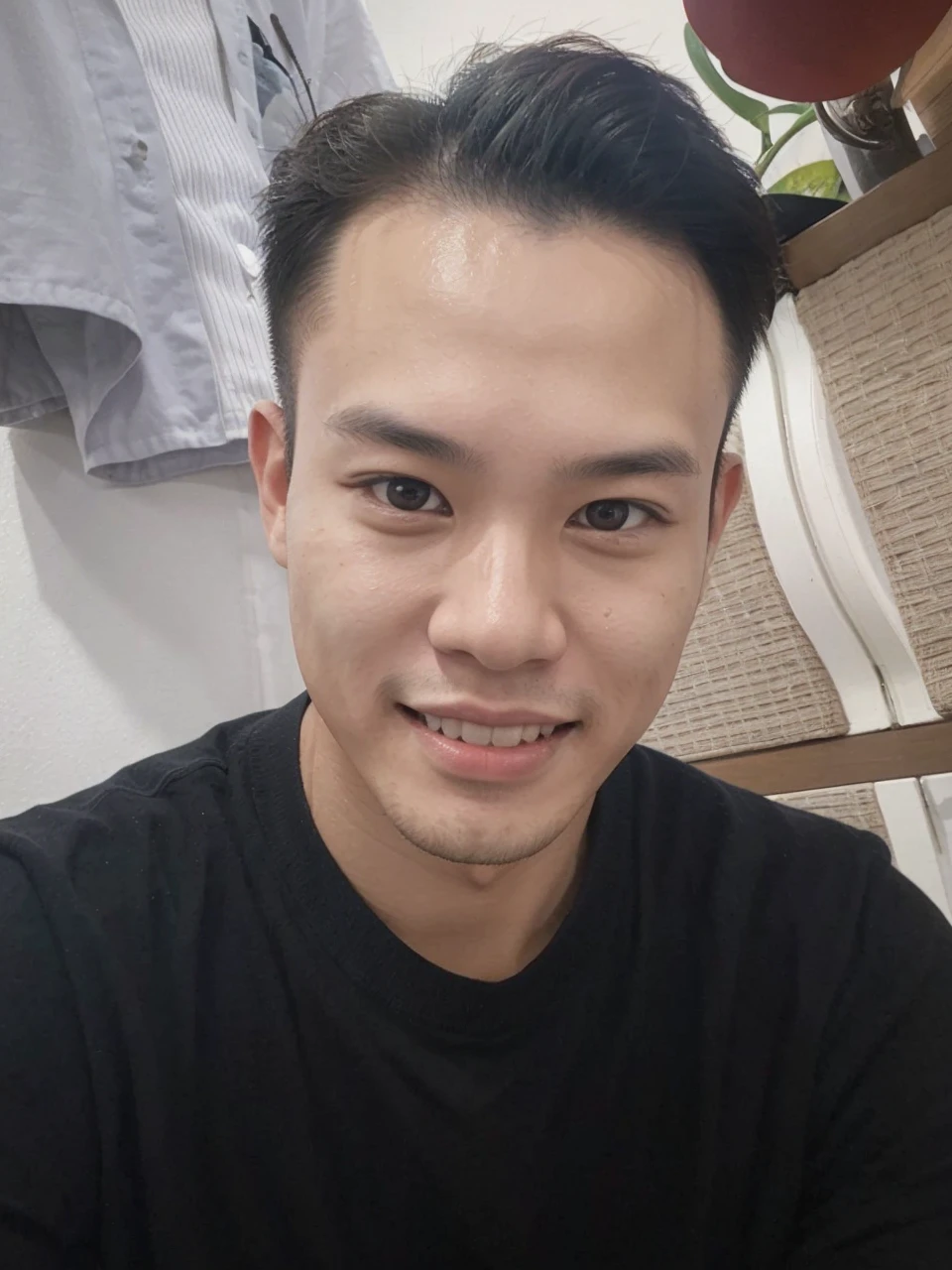 Capture Haruto Kim, a Korean-Thai man in his early twenties, in a spontaneous selfie style at a Tokyo café. He's wearing a white shirt and dark chinos, seated casually, giving the camera a friendly, relaxed smile. The photo should be taken as if with an iPhone, from a slightly raised angle typical of selfies. The café background is visible but not in sharp focus, creating a natural, everyday scene. The lighting is like that of a typical café, with no special effects, just the ambient, warm light of the setting.