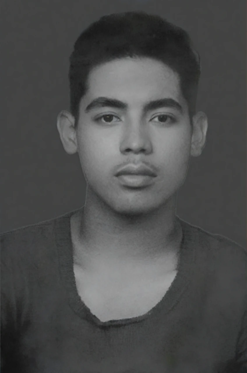 Portrait of a young man with a neutral expression, short dark hair with a fade cut, thick eyebrows, and fuller lips. The person has a medium skin tone, is wearing a dark crew-neck T-shirt, and the photo is in black and white, exhibiting a look reminiscent of the mid-20th century. The background is a solid, flat color. The image has a fine grain, giving it a vintage texture.