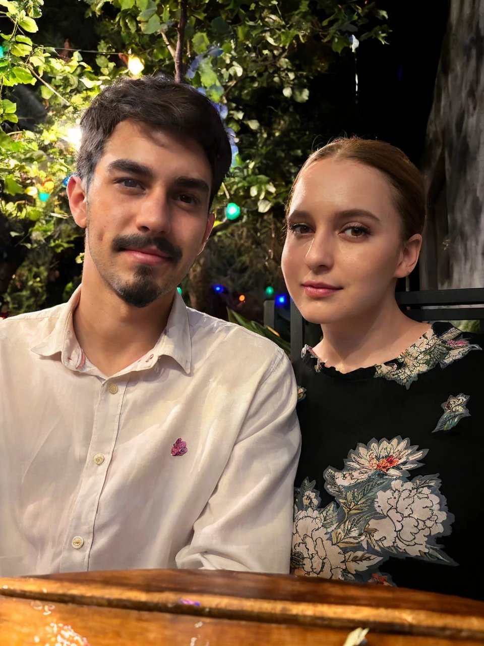 A beautiful woman and man with dark hair, dark brown eyes, and bright eyes, standing in a lush garden on a sunny day, surrounded by colorful flowers, with a cute expression and slightly split lips, blushing, in renesanse clothes 