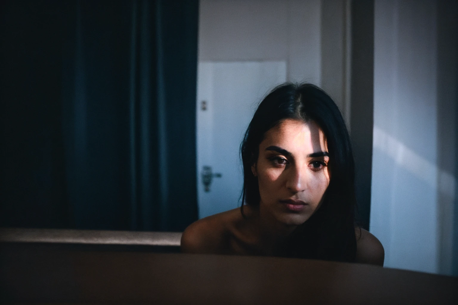 RAW photo,dark,moody,hazy atmosphere,35mm focal lenght,underexposed,cold,candid photograph,artistic,photograph of a beautiful,influencer,30yo Kurdish woman,detailed skin,fully naked,looking at viewer, candid pose,dim room,blue light, film grain, kodak color, instagram LUT