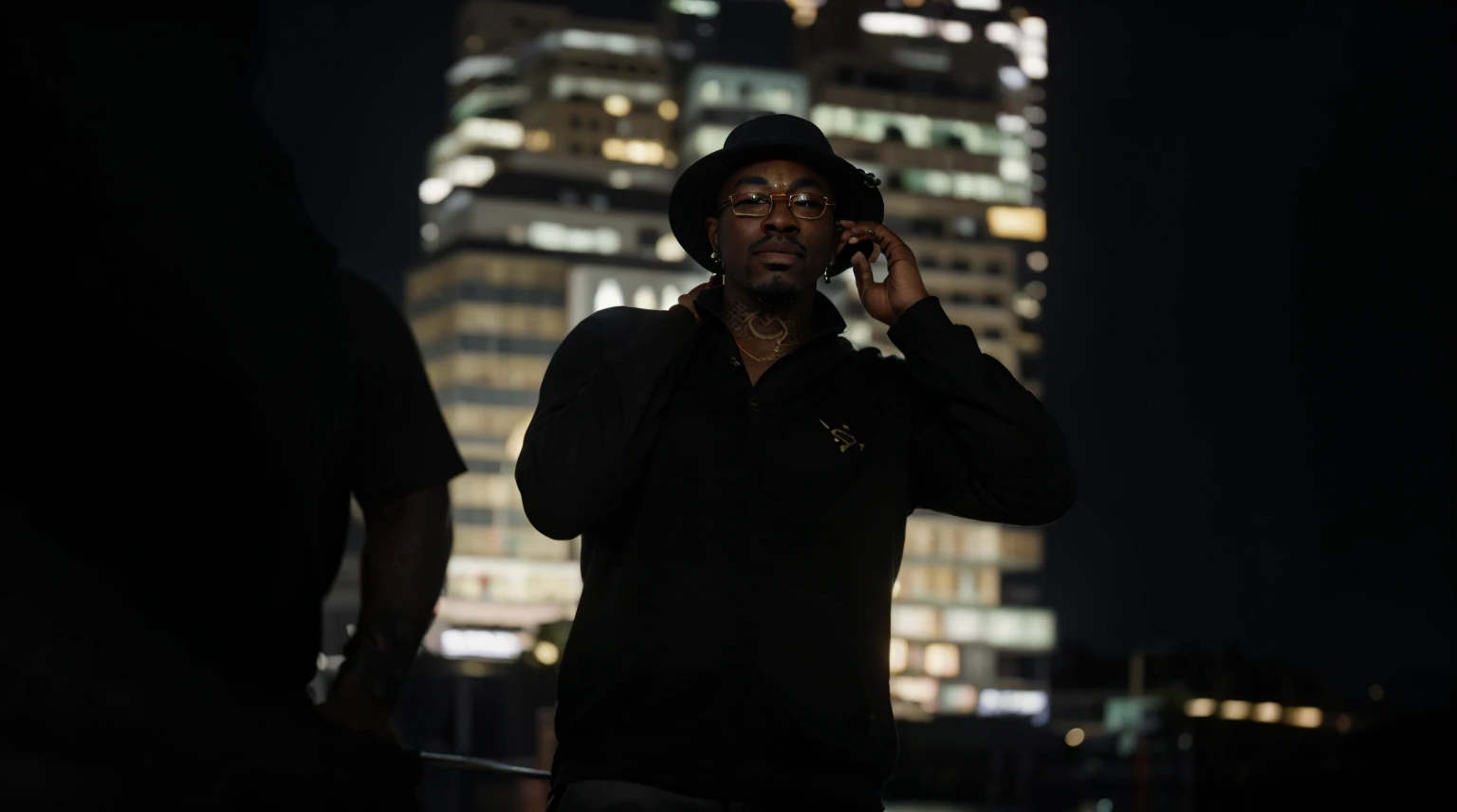 A dark-skinned man with face tattoos, goatee, elegant gold glasses, fishing hat with a chunk of money on his ear in Los Angeles at night, behind him is a large building at night