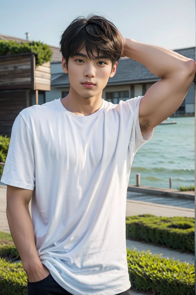 A young Asian man stands, handsome, muscular, looking at the camera. In a simple black t-shirt, Fieldside, grass, beach, sunlight