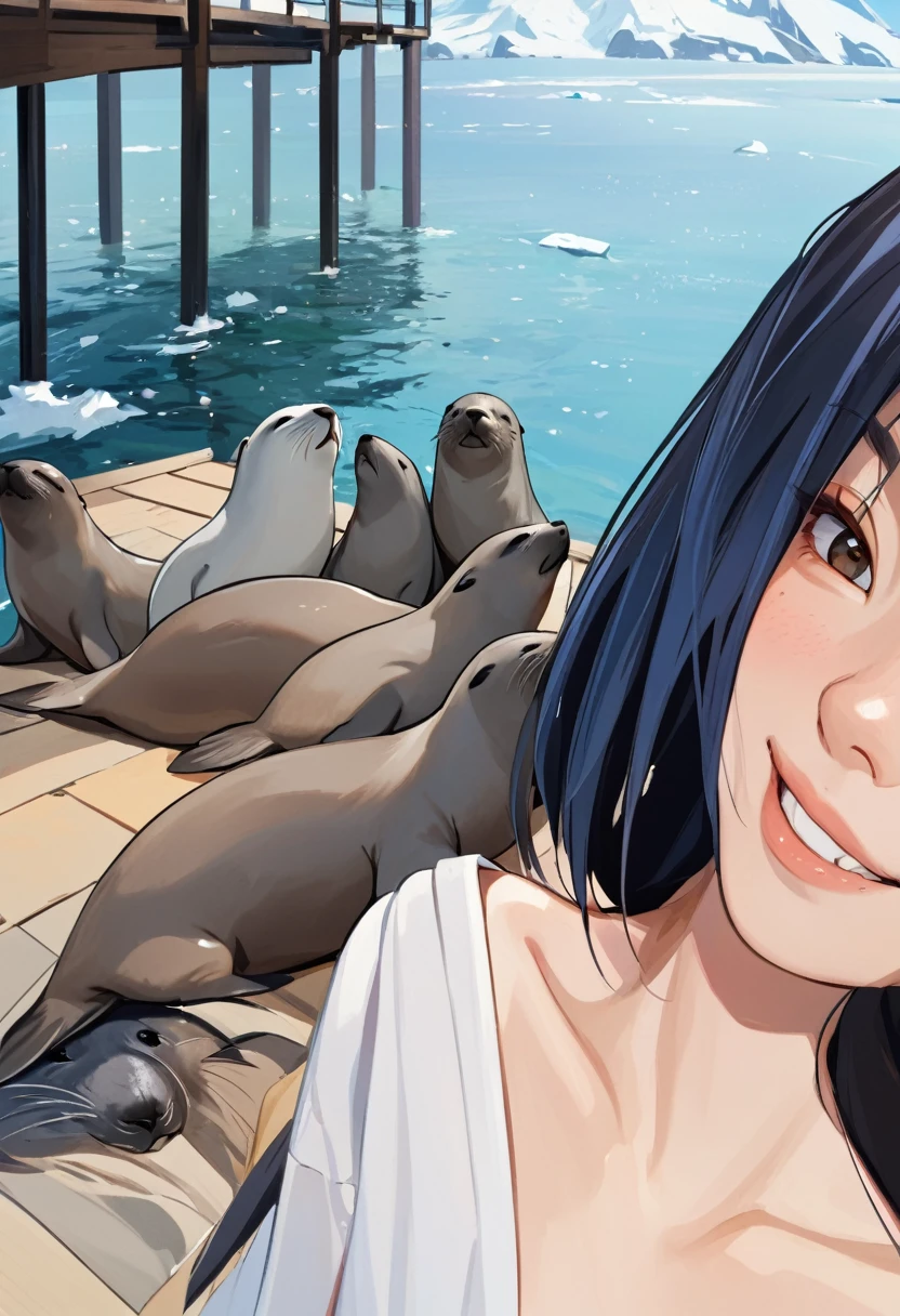 A girl takes a selfie with fur seals in the background, The girl smiles 