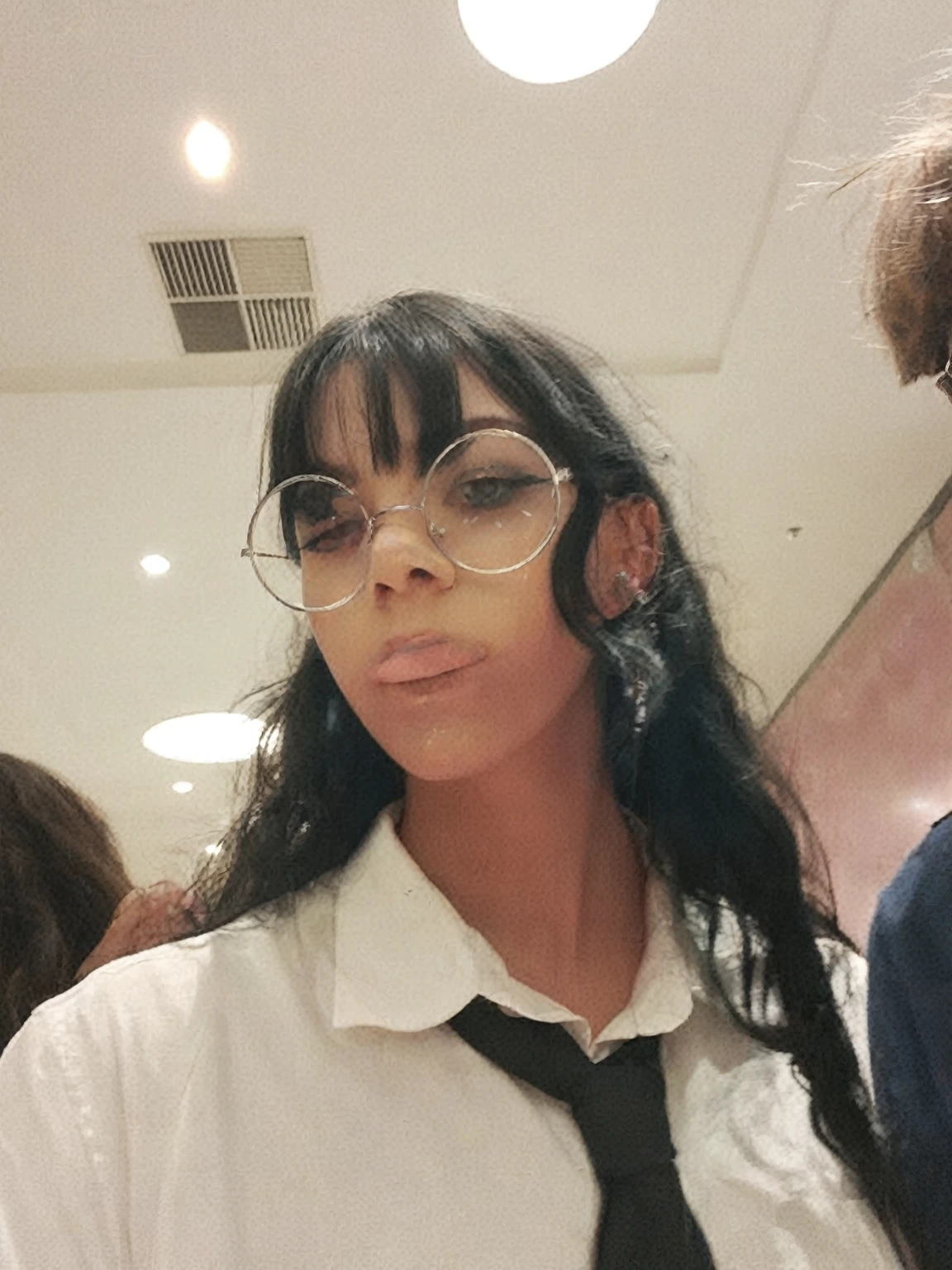 There is a woman with glasses and a tie standing in a room, Scary vibe, gothic mall, She wears Harry Potter glasses, scary look, Melanie Martinez, transparent face,  wearing round glasses, Bella Poarca, wearing clear glass mask, with haunted eyes and glasses, in style of petra collins, Clear glasses, girl at a fashion show in hell, spooky face