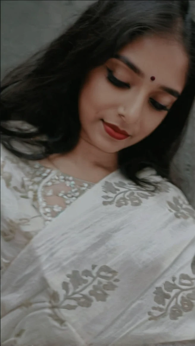 Create an AI influencer named Priya, a 25-year-old Indian woman with a blend of traditional and modern style. Priya has a dusky complexion, expressive dark eyes, and long, wavy black hair. She wears a vibrant silk saree paired with silver jhumkas (traditional earrings) and a bindi on her forehead. Describe her confident smile, the intricate henna patterns on her hands, and the scent of jasmine in her hair. Place Priya against the backdrop of a bustling Mumbai street, with colorful rickshaws and street vendors. Ensure her pose reflects both elegance and approachabilit