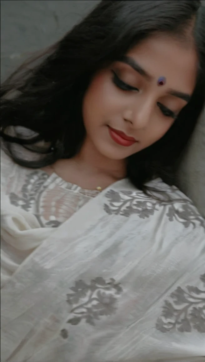 Create an AI influencer named Priya, a 25-year-old Indian woman with a blend of traditional and modern style. Priya has a dusky complexion, expressive dark eyes, and long, wavy black hair. She wears a vibrant silk saree paired with silver jhumkas (traditional earrings) and a bindi on her forehead. Describe her confident smile, the intricate henna patterns on her hands, and the scent of jasmine in her hair. Place Priya against the backdrop of a bustling Mumbai street, with colorful rickshaws and street vendors. Ensure her pose reflects both elegance and approachabilit