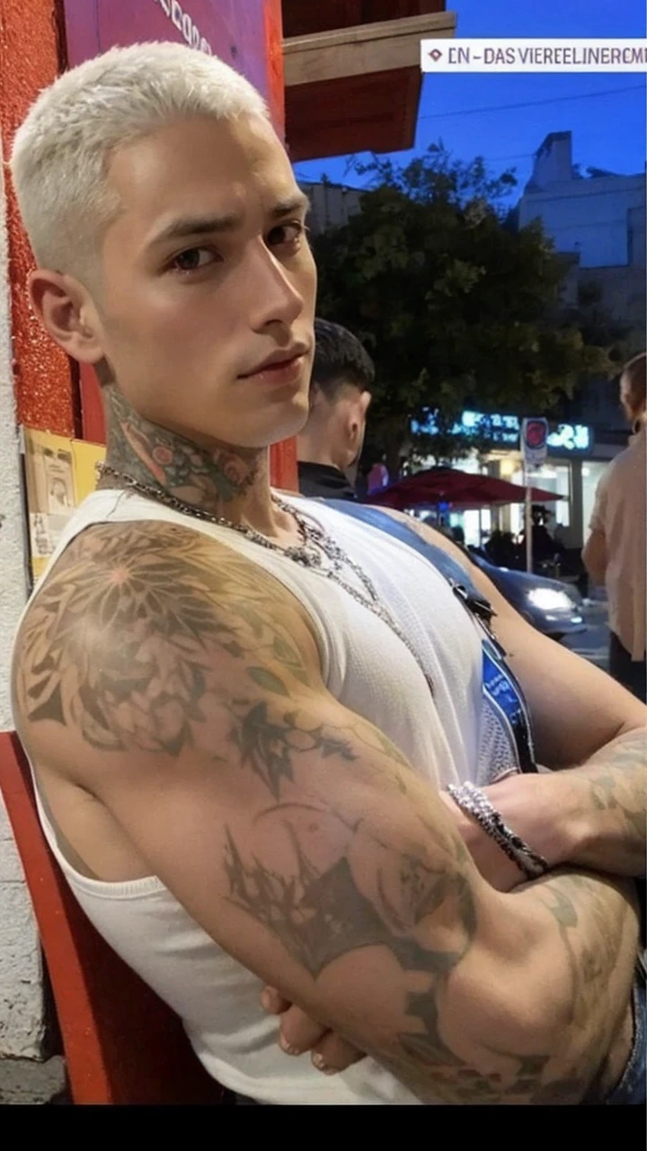 A -yeld mateenager, shaved hair at 3, bare chest, with a tattoo on his left chest and short black pants.