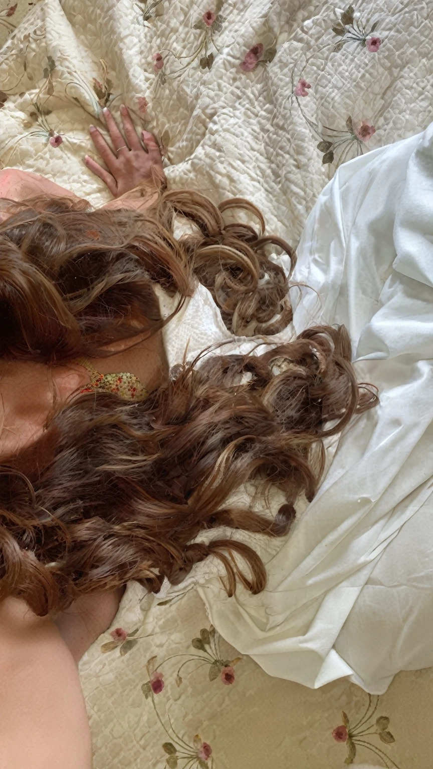 there is a woman laying on a bed with her head on a pillow, brown curly hair, curly brown hair, brown flowing hair, with brown hair, hair dyed to a hazelnut brown, long flowing brown hair, brown wavy hair, brown messy hair, curls, long curly brown hair, curled slightly at the ends, messy brown hair, curls hair, brown haired