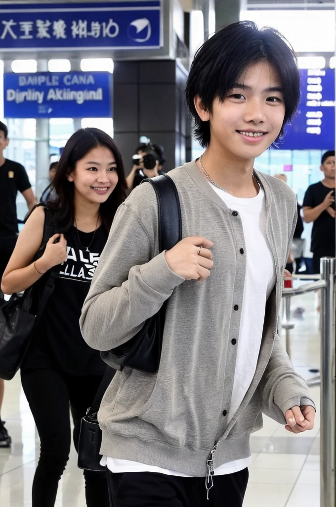 An Indonesian Malaysian boy has a big smile on his face, while standing at the airport and being photographed by paparazzi. He has a modern clothing style, black hair, world, yes also well styled he has dimples 