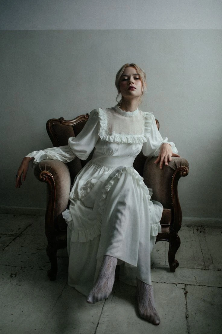 A 20 year old woman.  Blonde Hair: Long and blond, often loose or styled into elegant hairstyles.Blue Eyes: Light blue eyes that highlight her angelic expression.Fair Skin: Fair and smooth skin, often described as porcelain.Height: 1.57 m, maintaining a graceful and delicate appearance. Delicate face: Delicate facial features with high cheekbones and an ethereal expression.