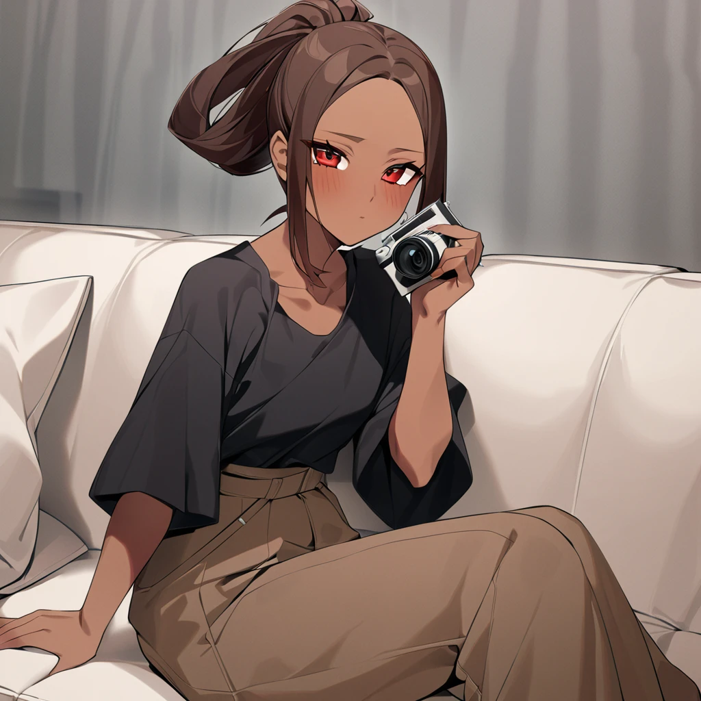 A woman with brown skin and red eyes, and long hair tied in a long, voluminous ponytail. She wears extra-oversized brown pants and a black blouse. She is sitting on a sofa, as if taking a photo while having a bout of shyness.