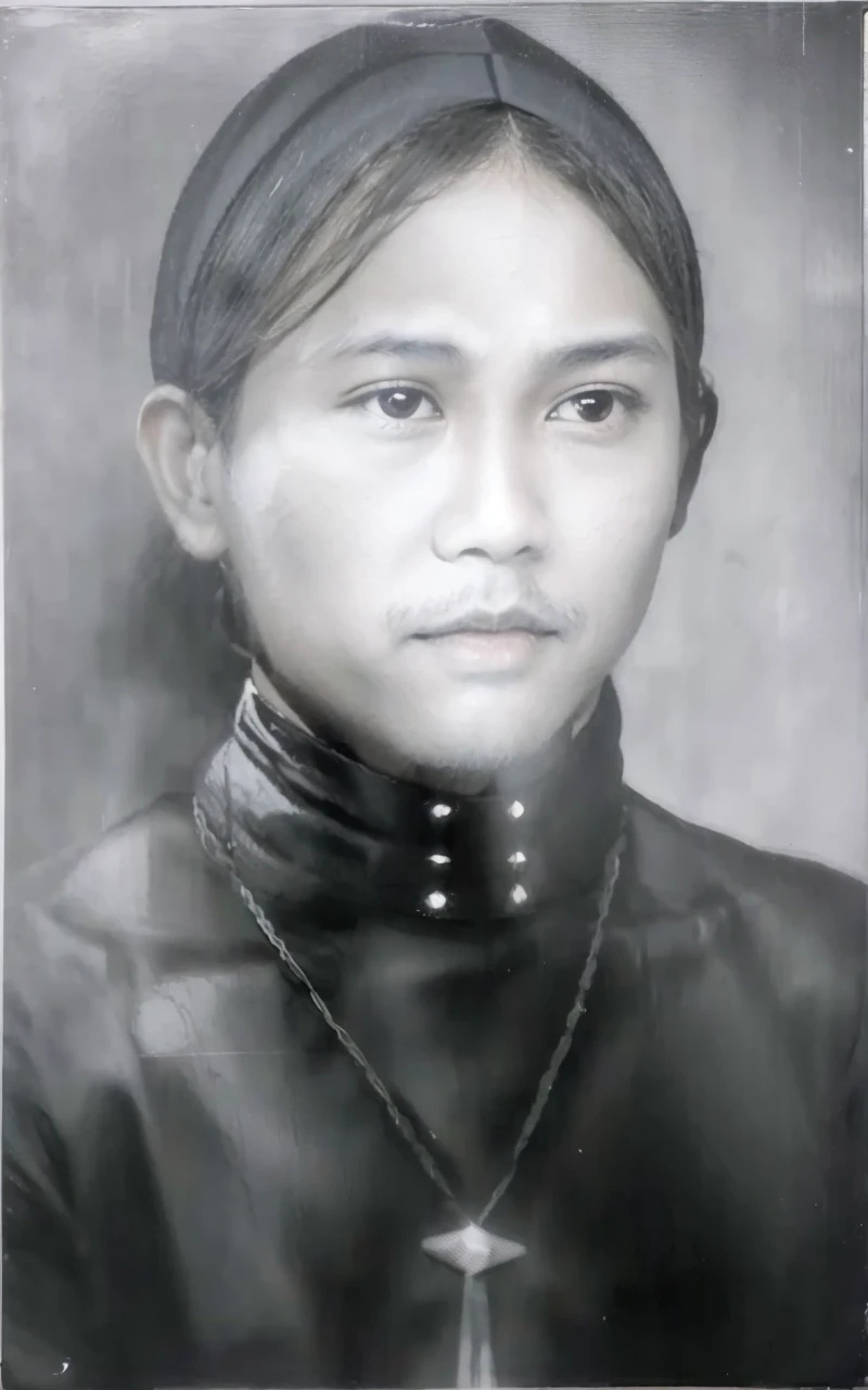 Indonesian Muslim man, 45 years old, brown skin with wrinkles according to age. small, closed lips, long natural black eyebrows, clean shining black eyes. flat nose. oval face, long chin. thin mustache and beard. wearing a black head covering, perhaps a type of blangkon, and kanigaran type clothes with the nuances of a prince. You can see a necklace hanging around the neck with a long, horizontal jewel-like fruit with a realistic HD quality image.