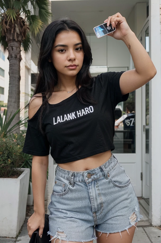 a young latina woman, with black hair that falls over her shoulders, she is wearing a black t-shirt, she takes a selfie, she is holding a credit card in her right hand 