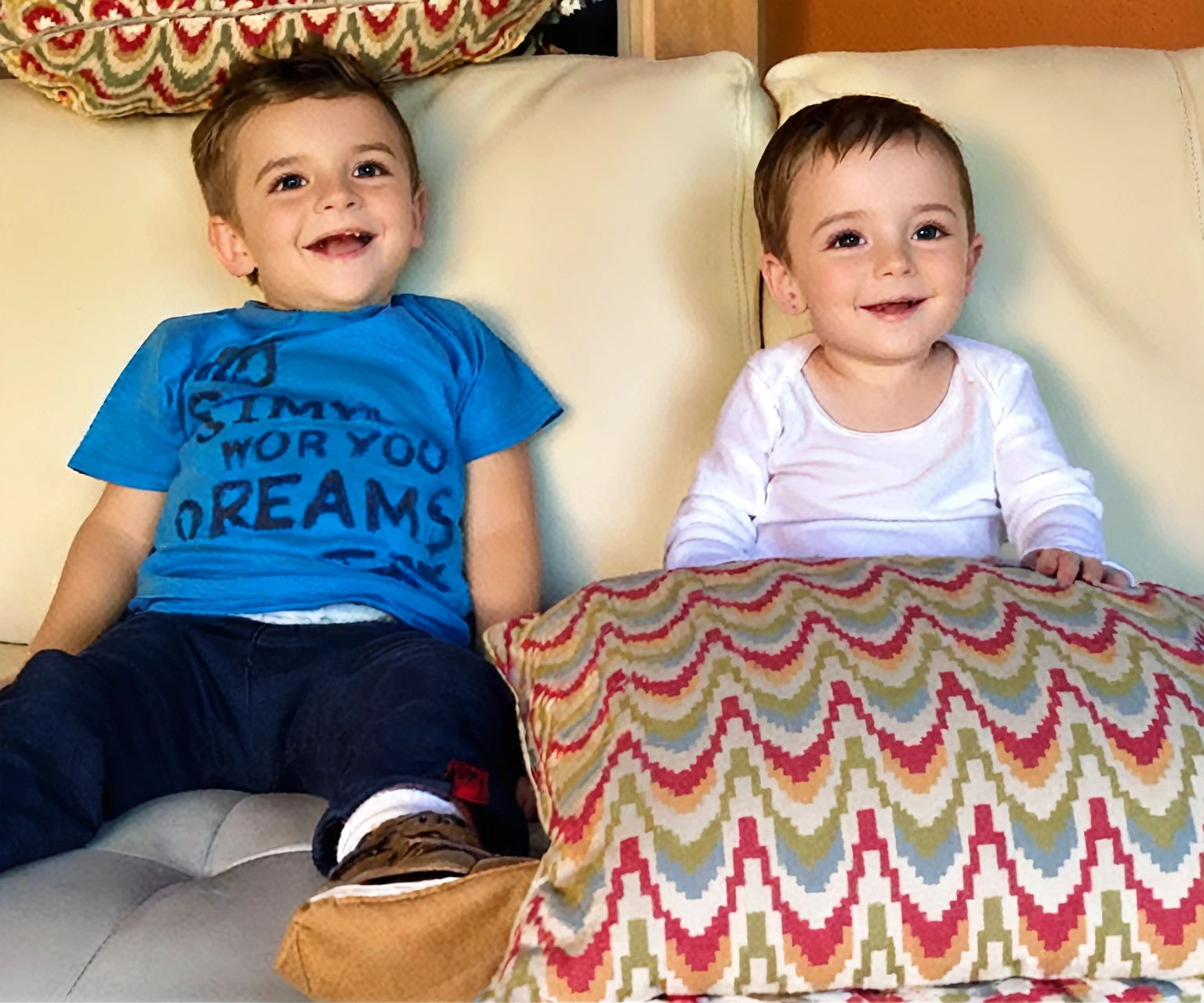 there is a boy and a woman sitting on a sofa with cushions, they are smiling, gorgeous faces, sweet appearance, They are close to each other. put them at with the same characteristics