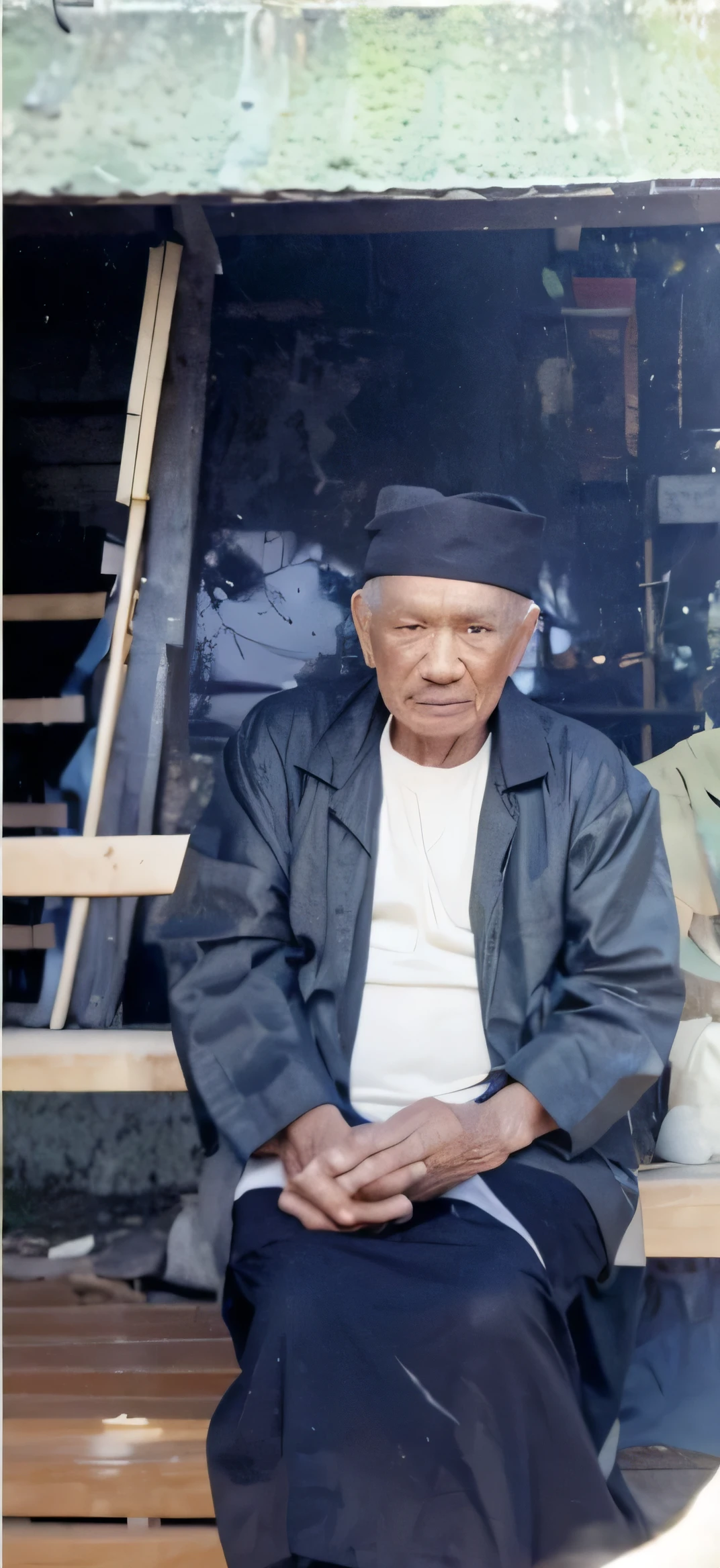 Hyper realistic 80-year-old grandfather from Indonesia wearing a black sarong is sitting in front of his house while crossing his legs