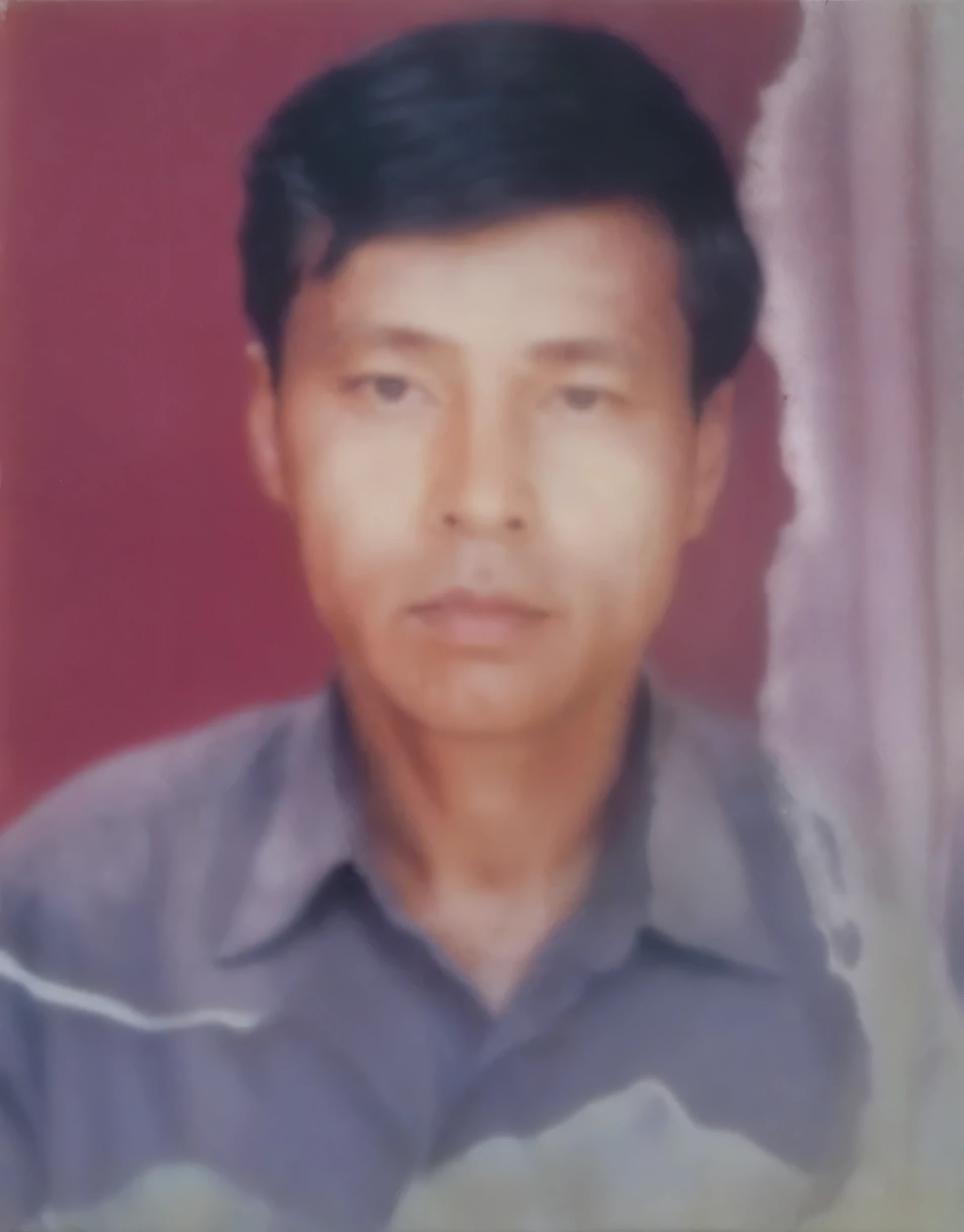 "Restore and enhance an old photograph of a man in a grey shirt with a red background, removing damage and improving clarity."